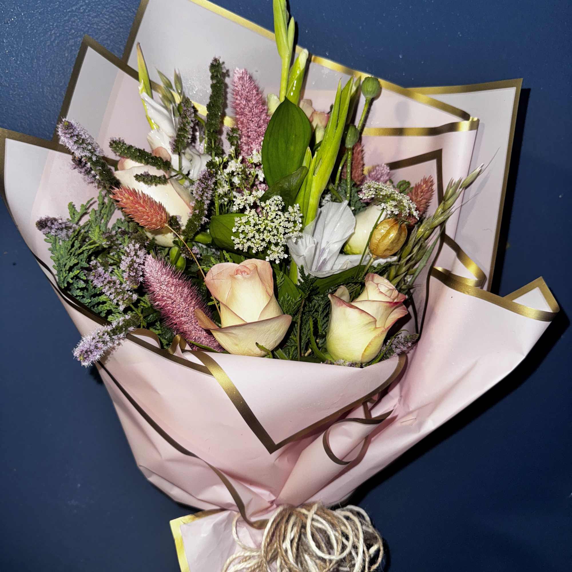 Bouquet of pale pink roses and mixed blooms wrapped in pink paper