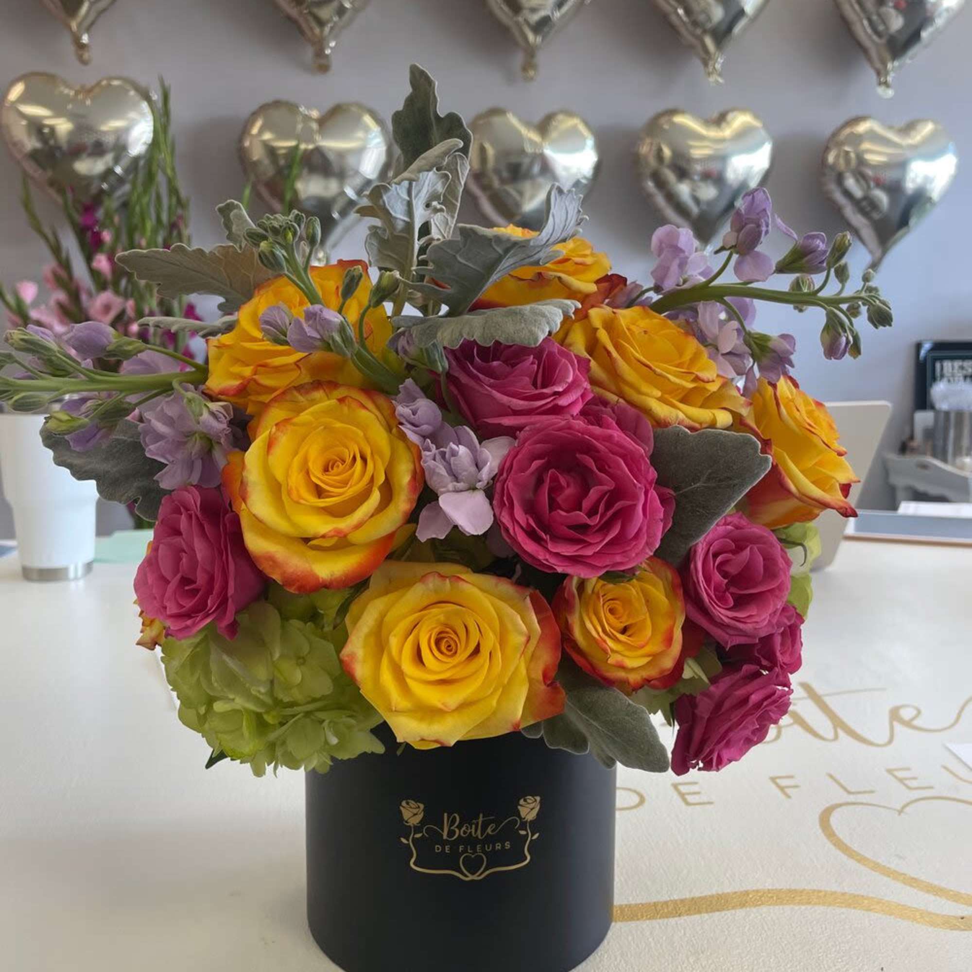 Yellow and pink roses arranged in a black hat box