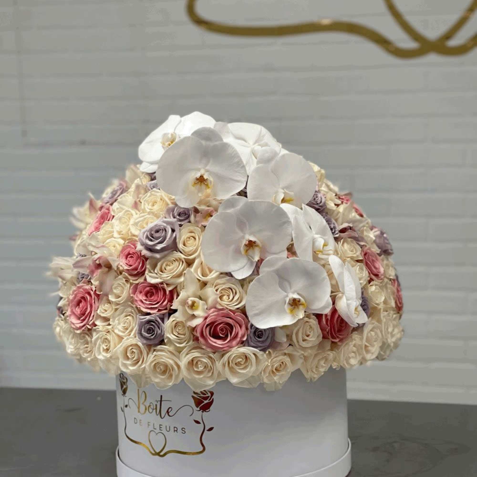 Round box arrangement of white orchids and pastel roses