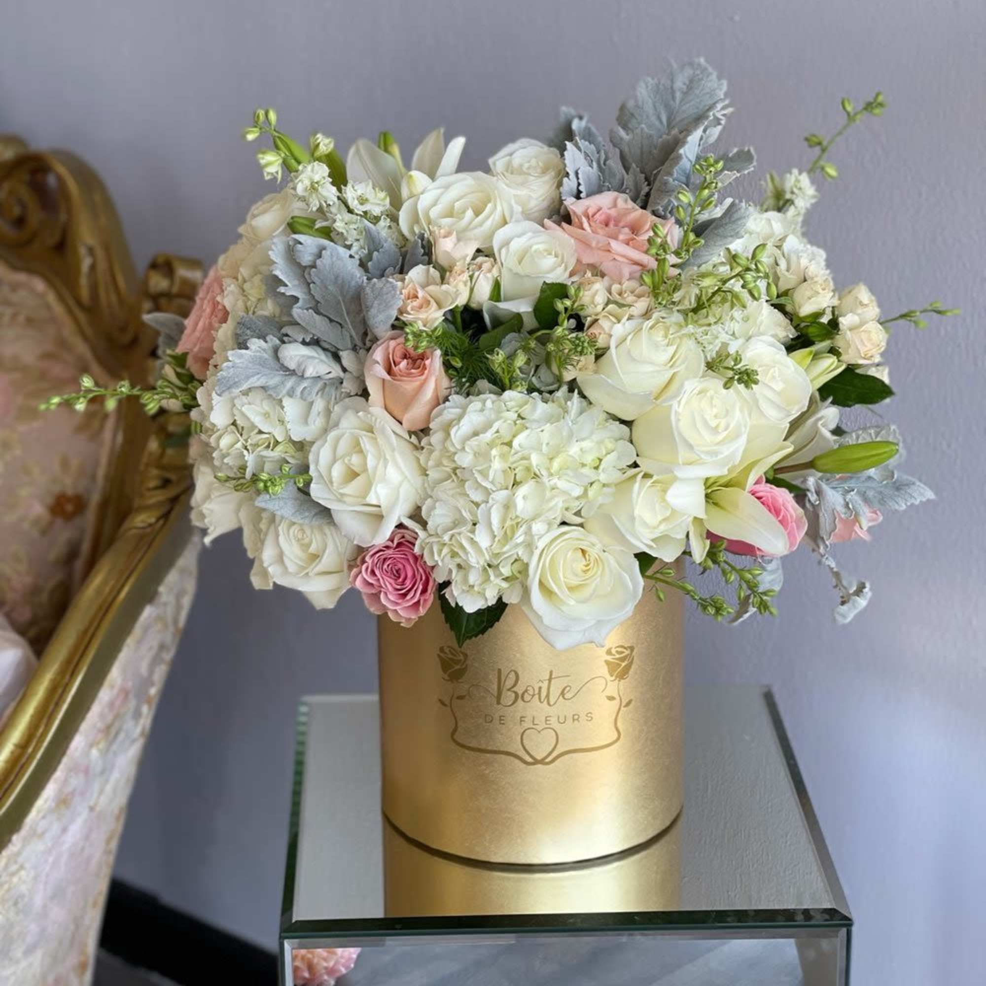 White and blush roses arranged in a gold hat box