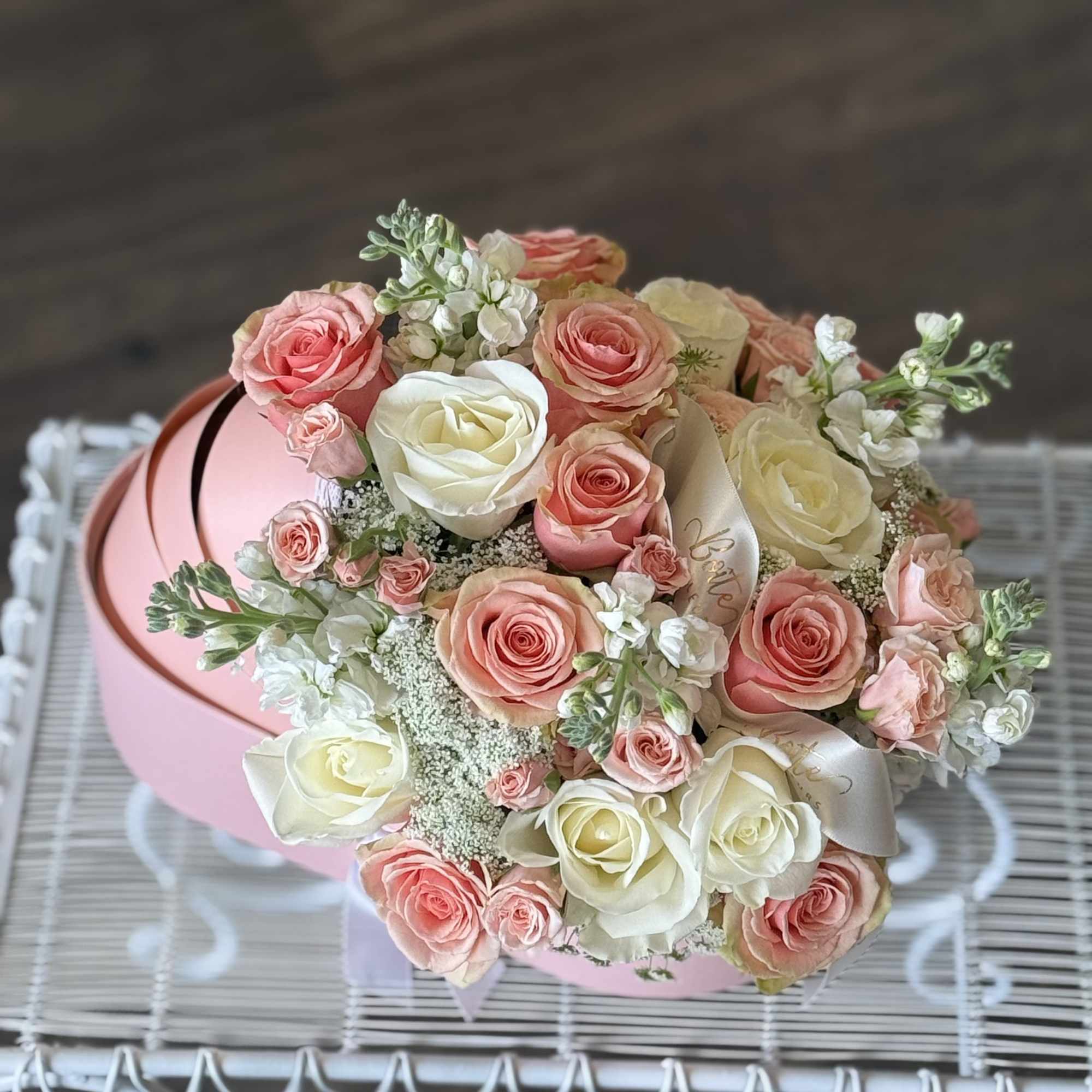 Bouquet of pink and white roses in a round pink box
