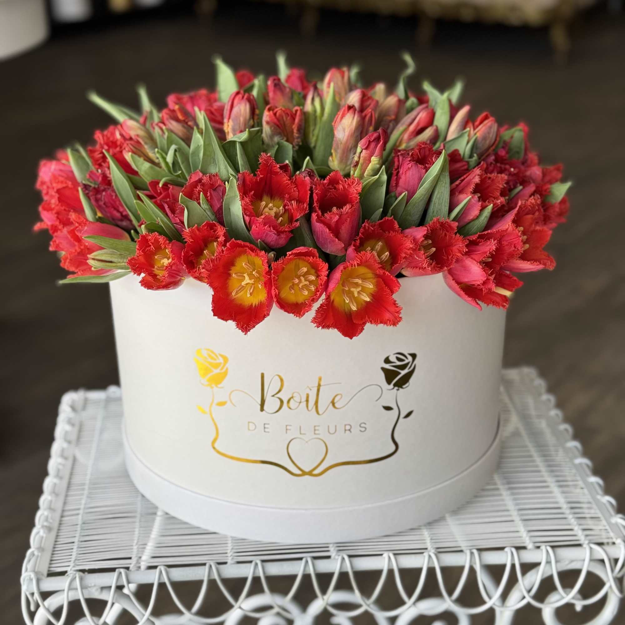 Round box of red tulips with green leaves