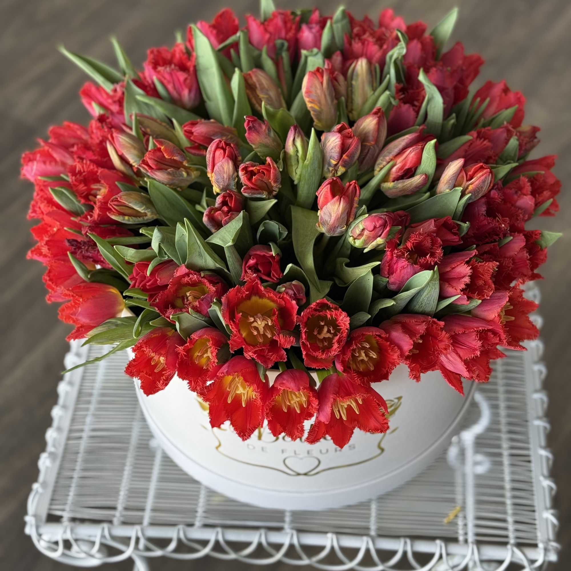Round bouquet of red tulips in a white hatbox