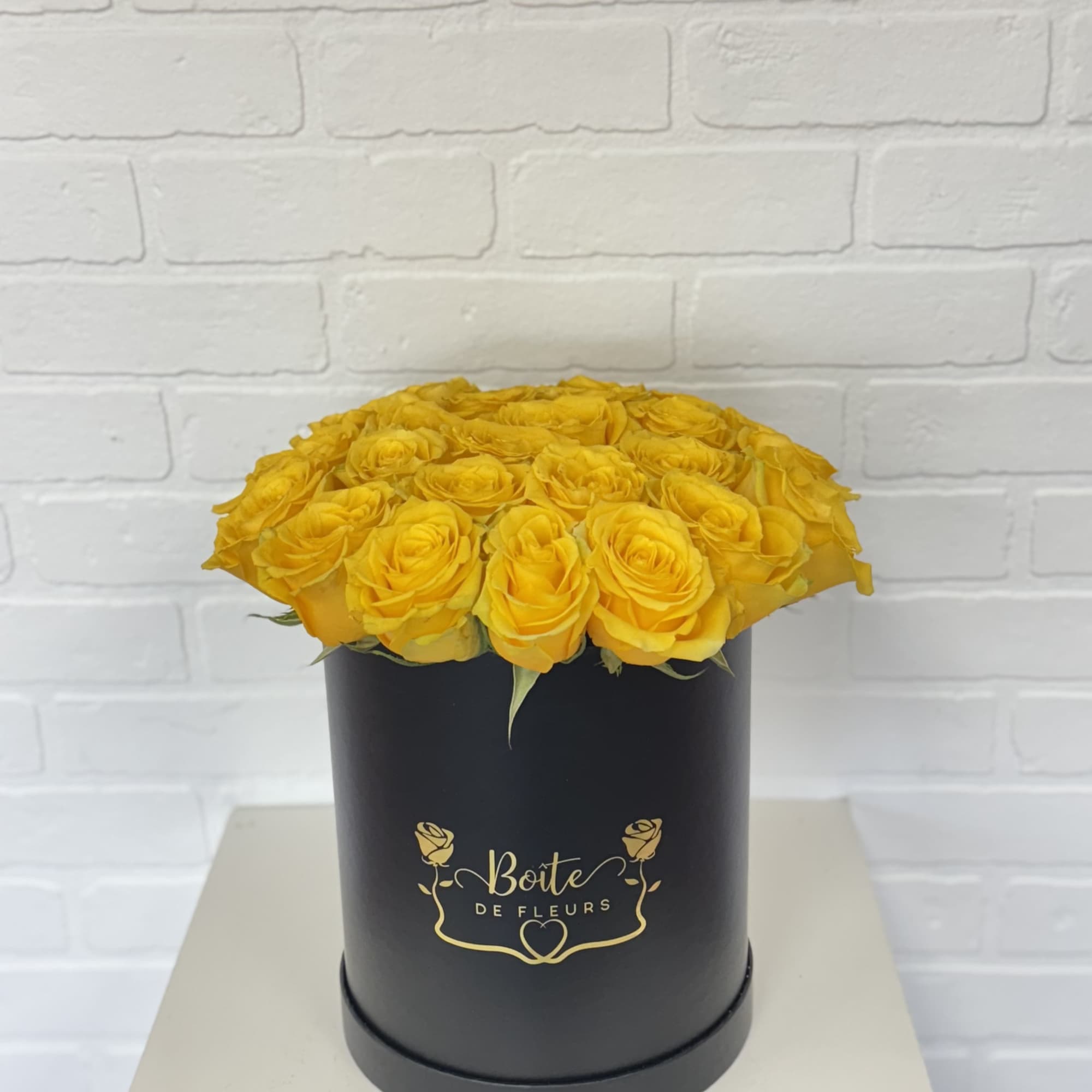 Yellow roses arranged in a black cylindrical box