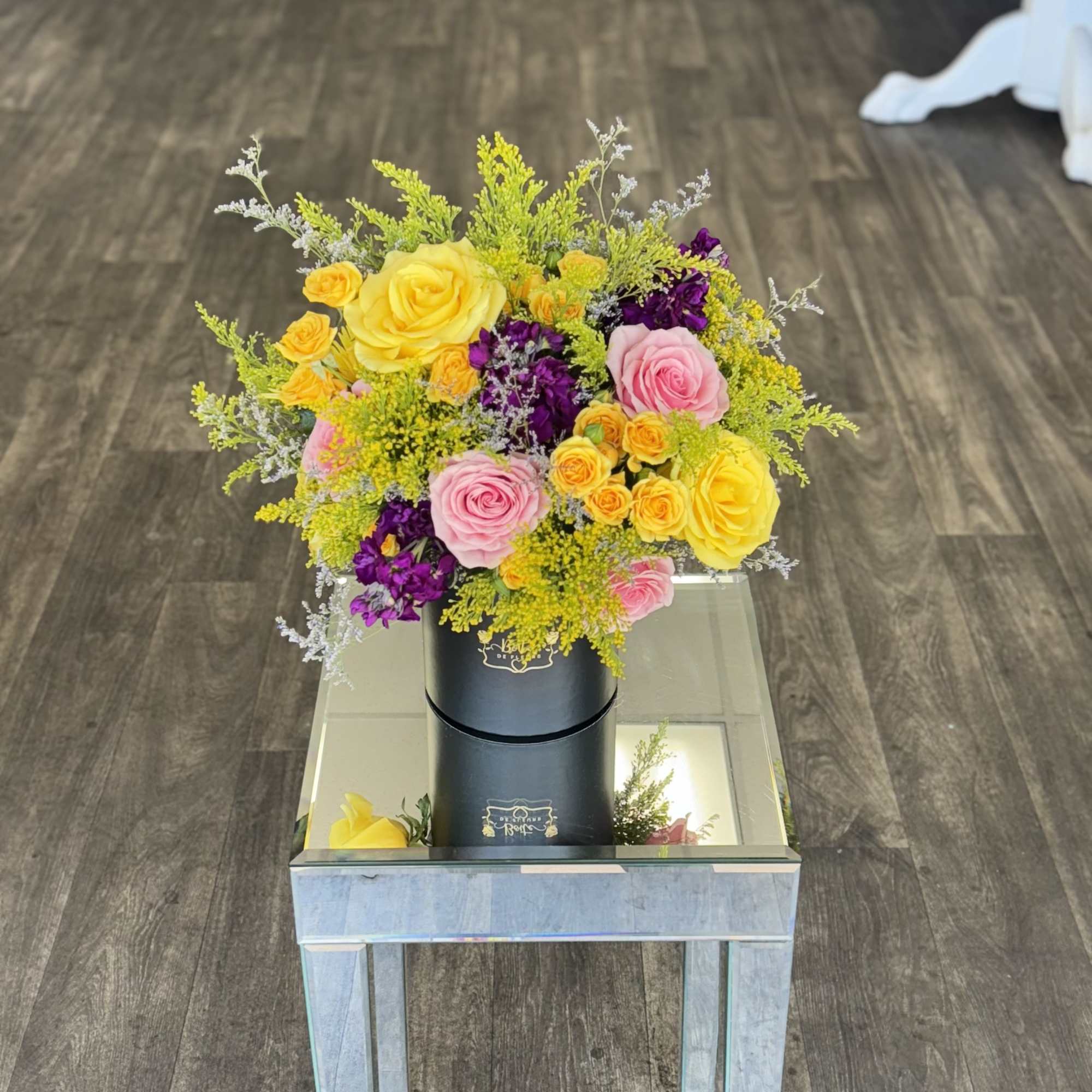 Bright bouquet of yellow, pink, and purple roses in a black box