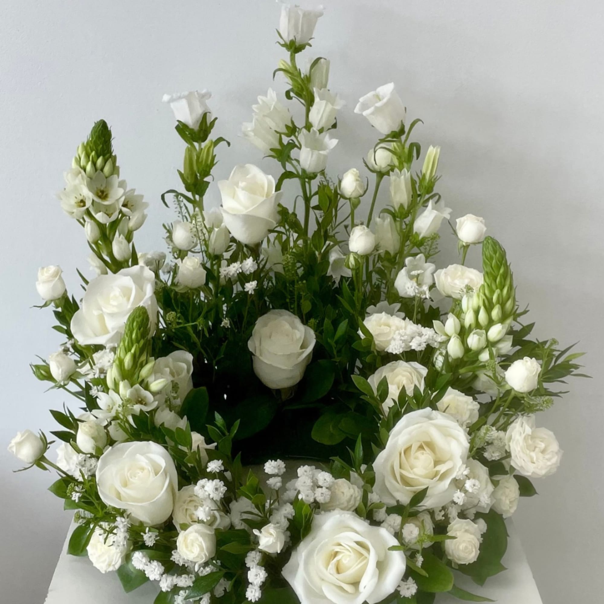 White roses and mixed white blooms arranged in a low, rounded display