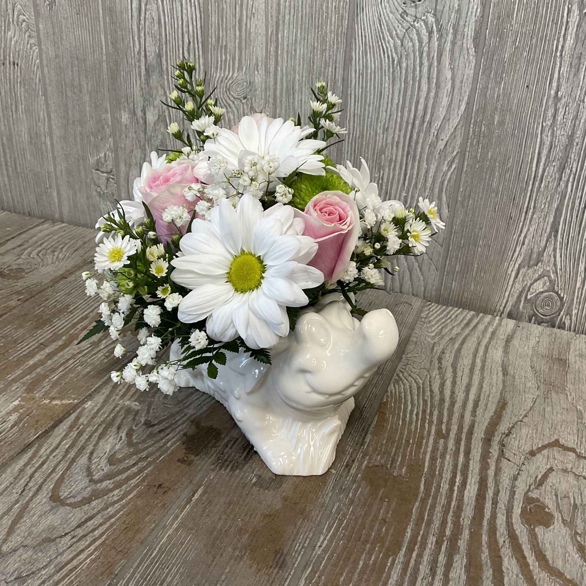 Pink roses and white daisies in a white ceramic frog planter