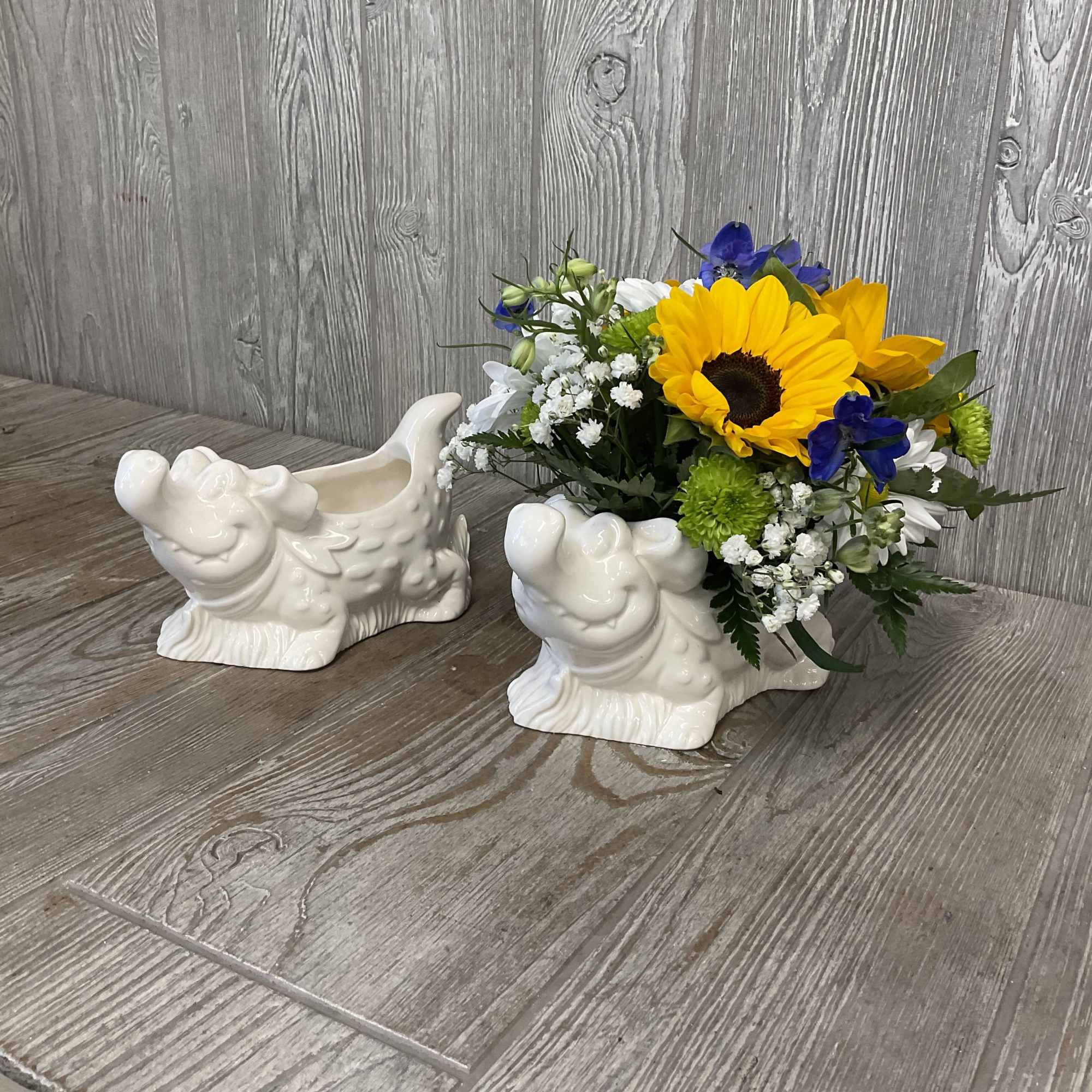 Flower arrangement in a white ceramic frog planter with yellow and blue blooms