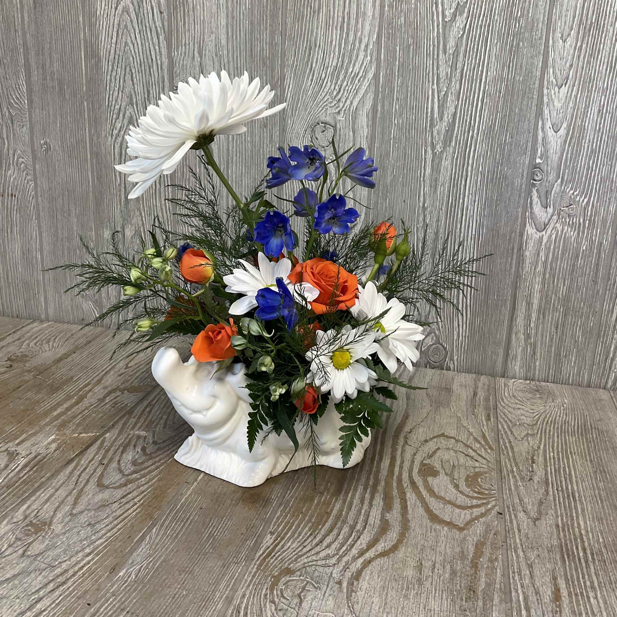 Colorful flower arrangement in a white ceramic swan planter