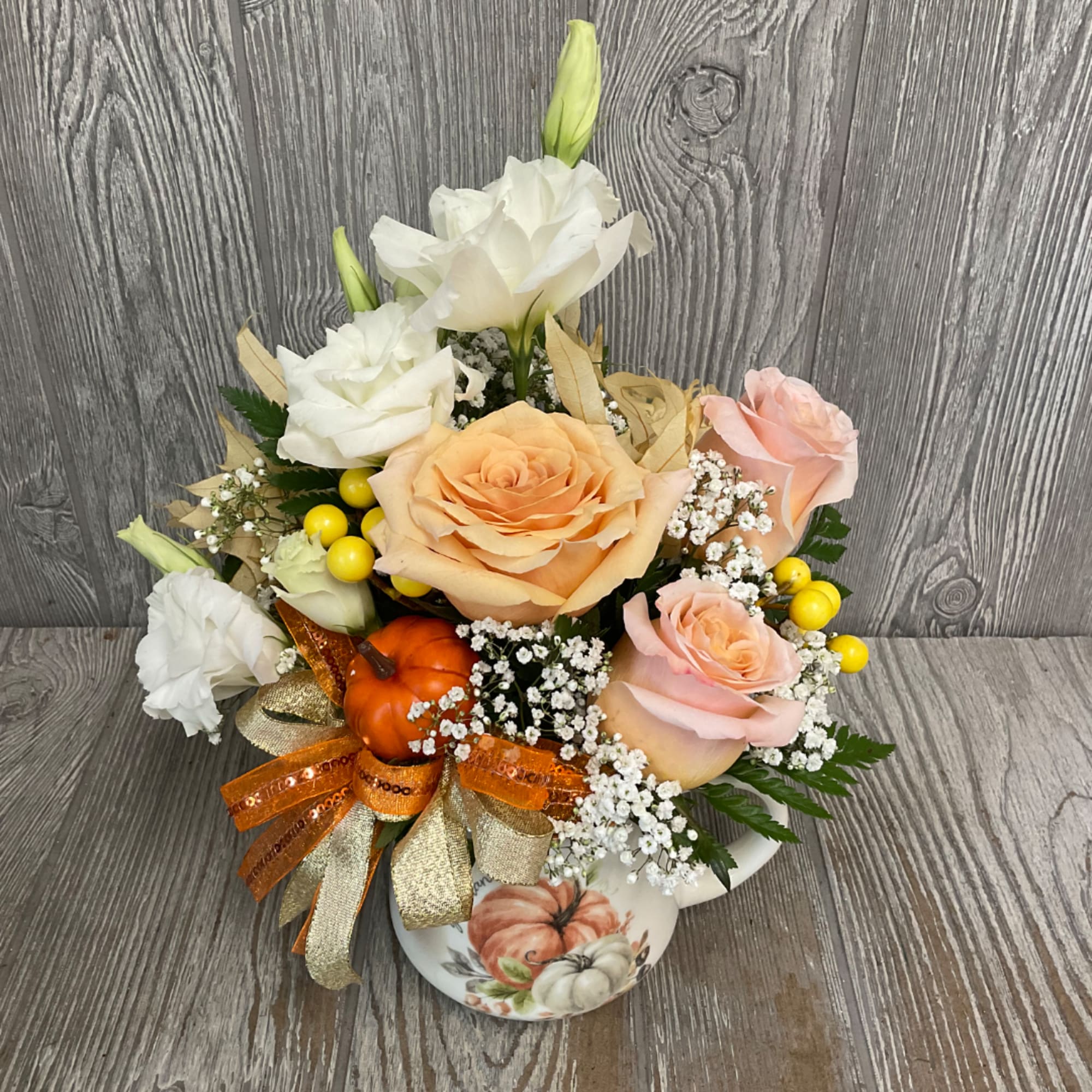 Peach and white roses with white lisianthus in a pumpkin vase