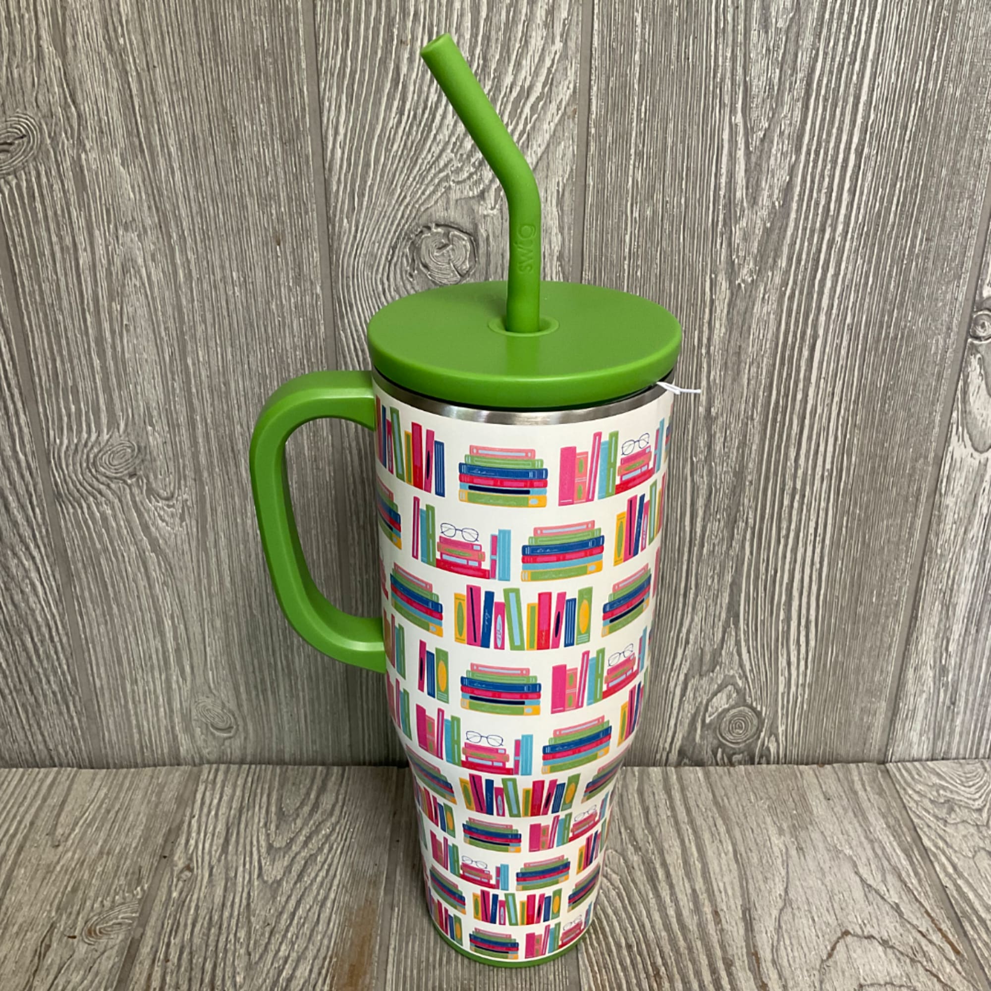Green handled tumbler with lid and straw, covered in colorful book illustrations