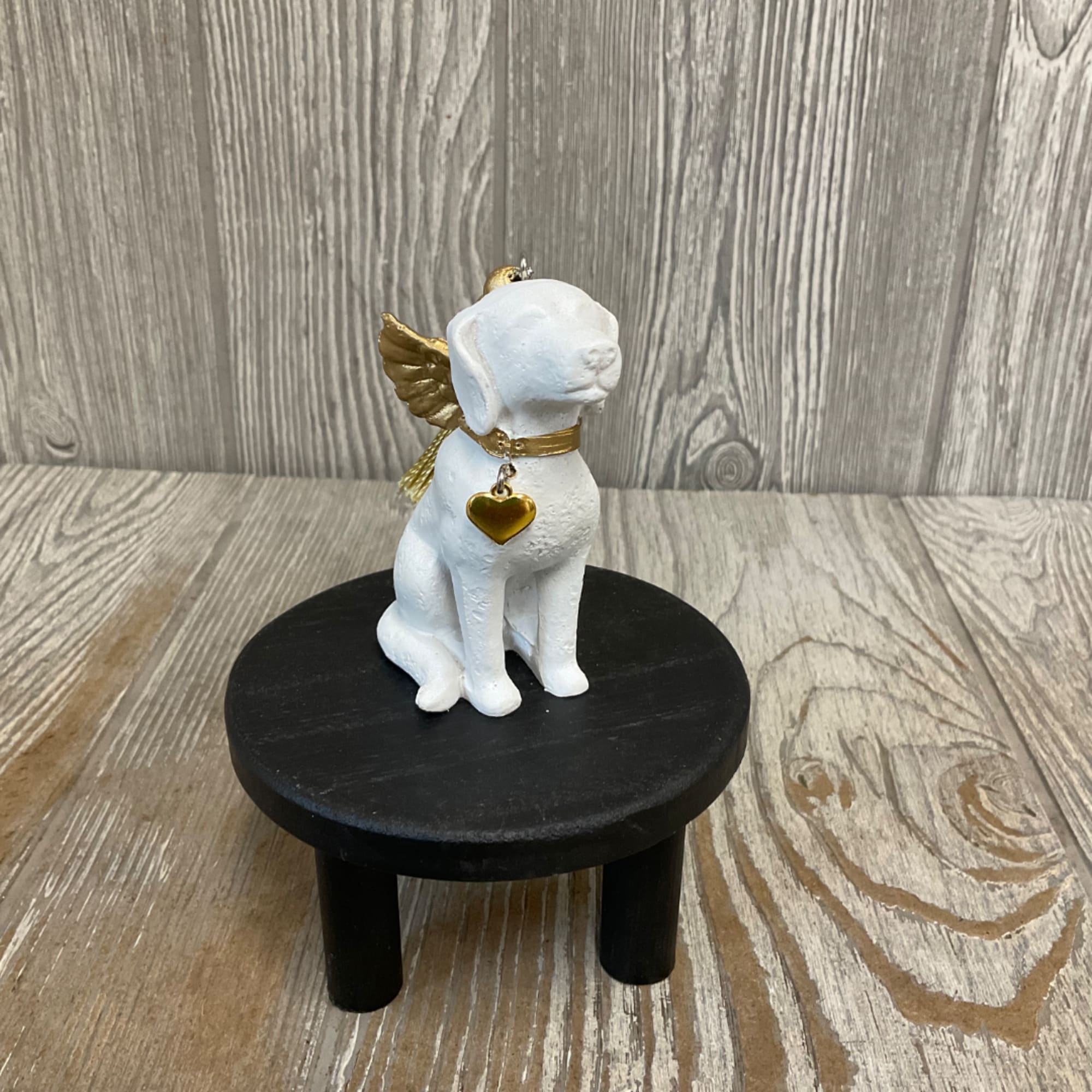 White dog figurine with gold wings and heart charm on a black stand