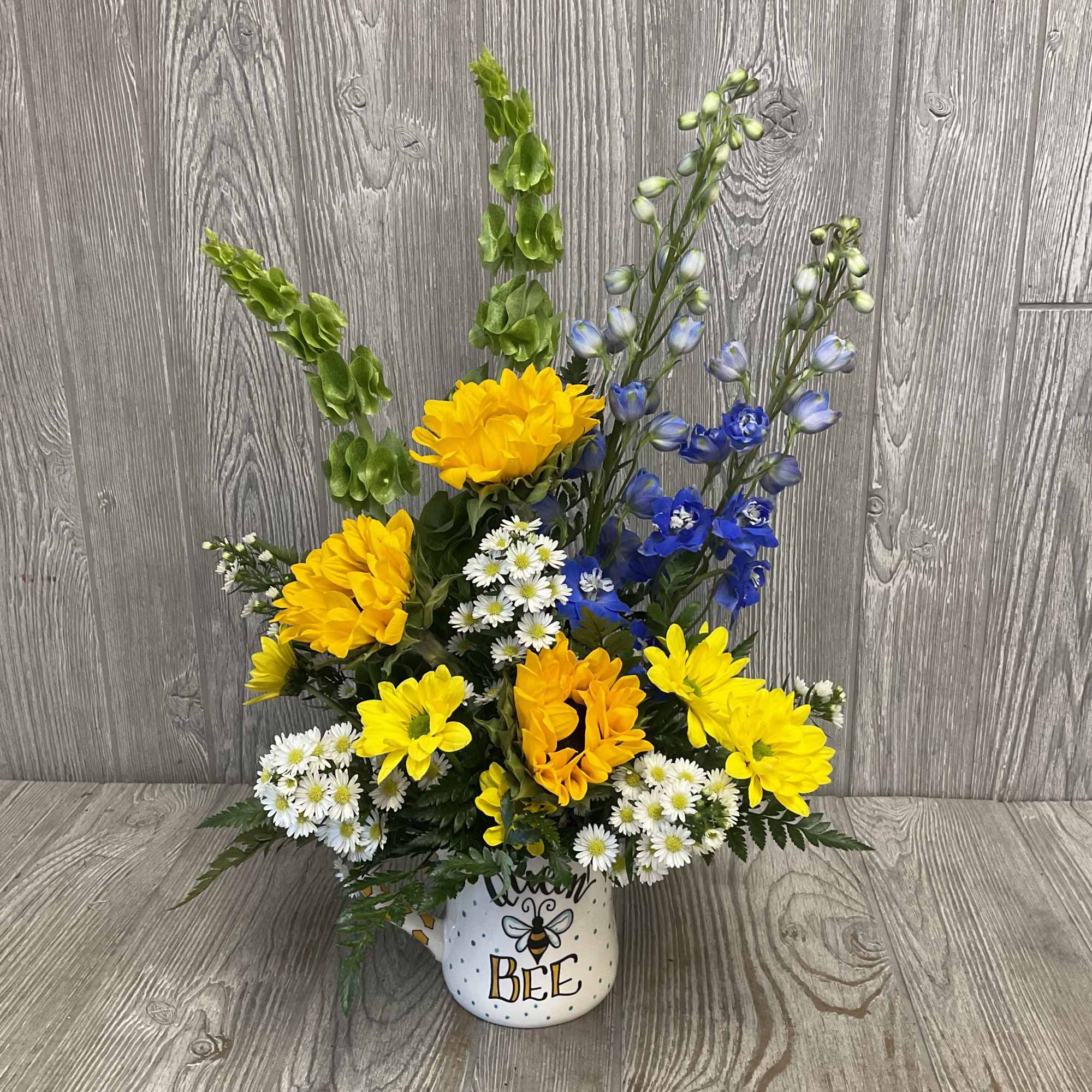 Yellow and blue flowers arranged in a bee-themed mug