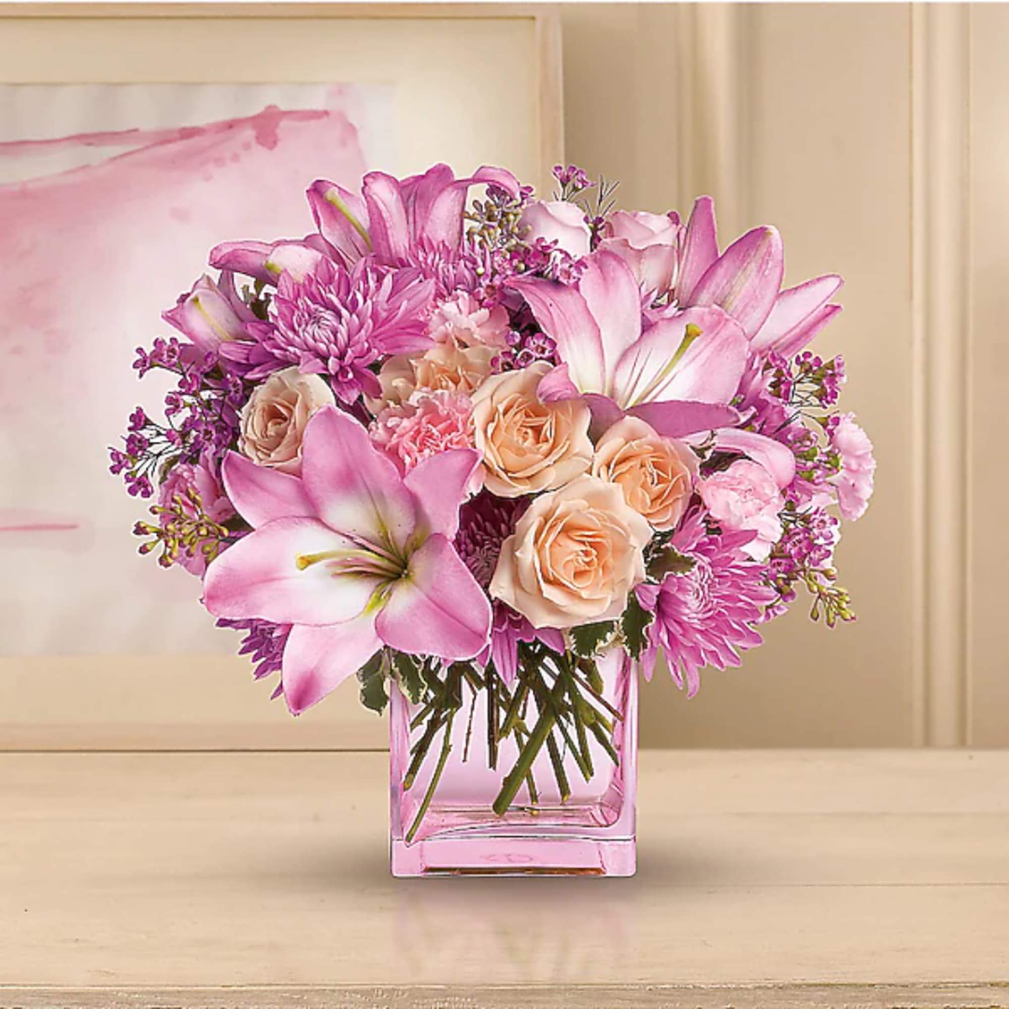Pink lilies, roses, and chrysanthemums in a square glass vase