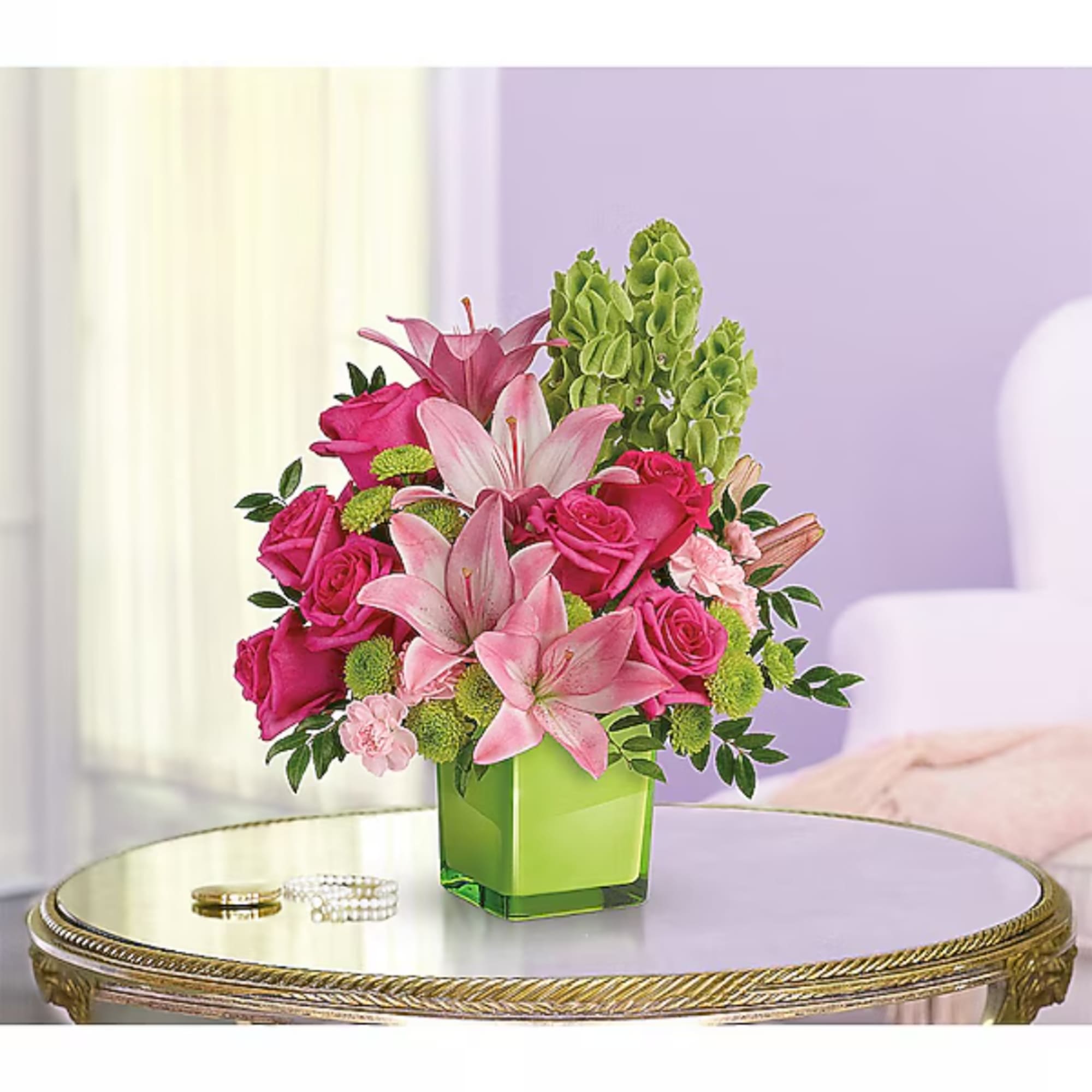 Pink roses and lilies arranged in a green square vase