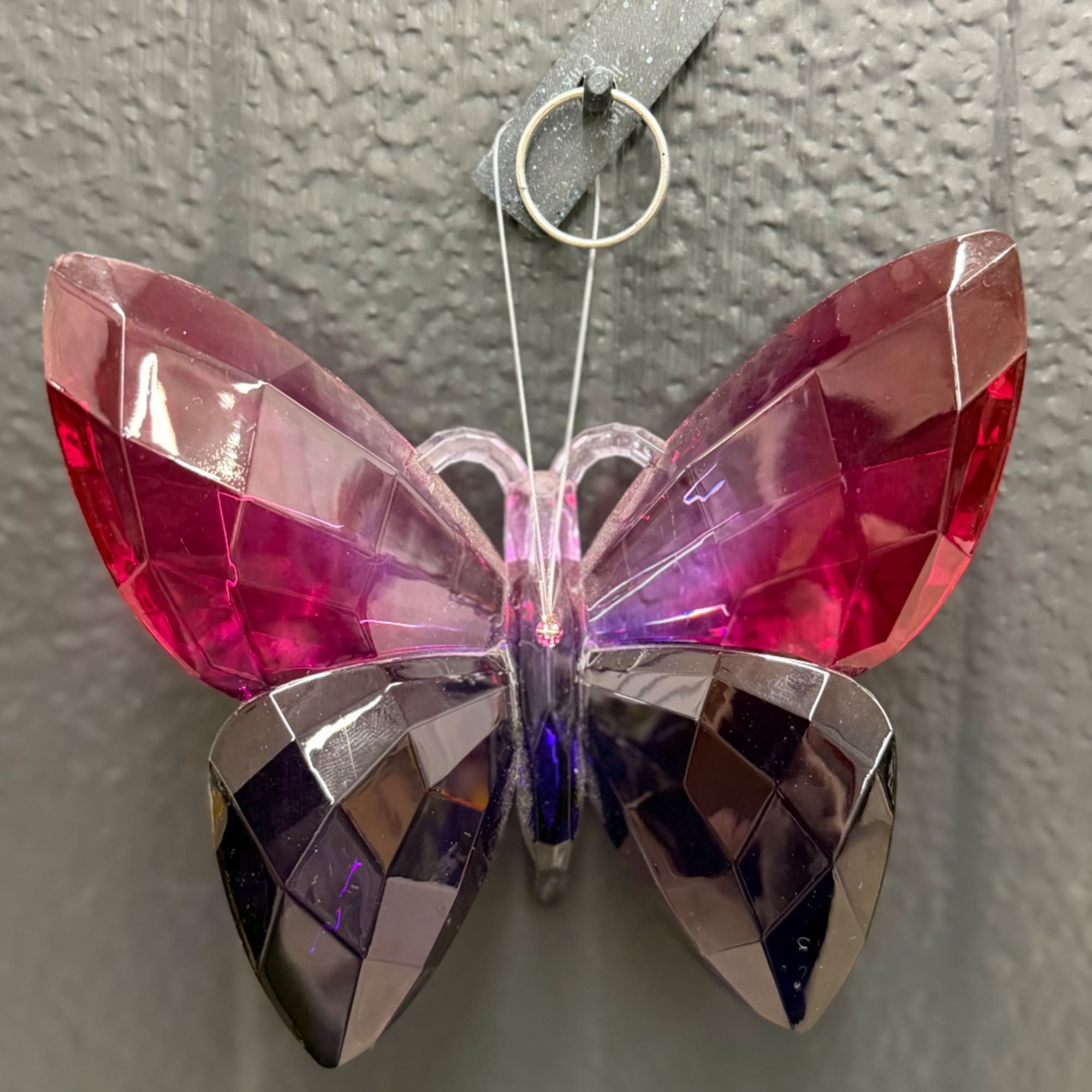 Faceted pink and purple butterfly ornament hanging on a wall