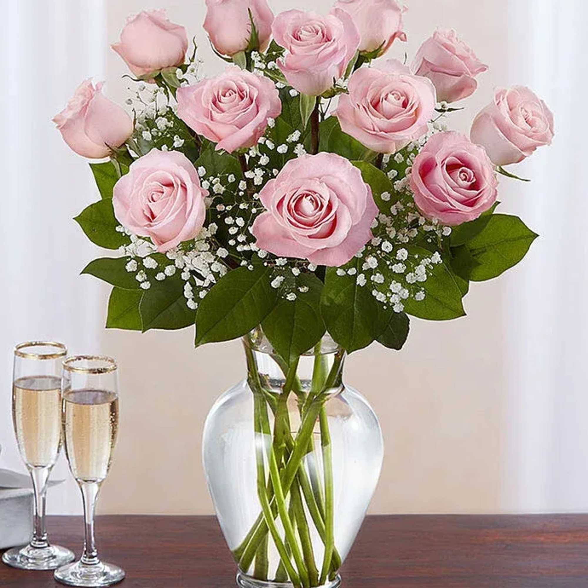 Pink roses arranged in a clear glass vase with baby's breath