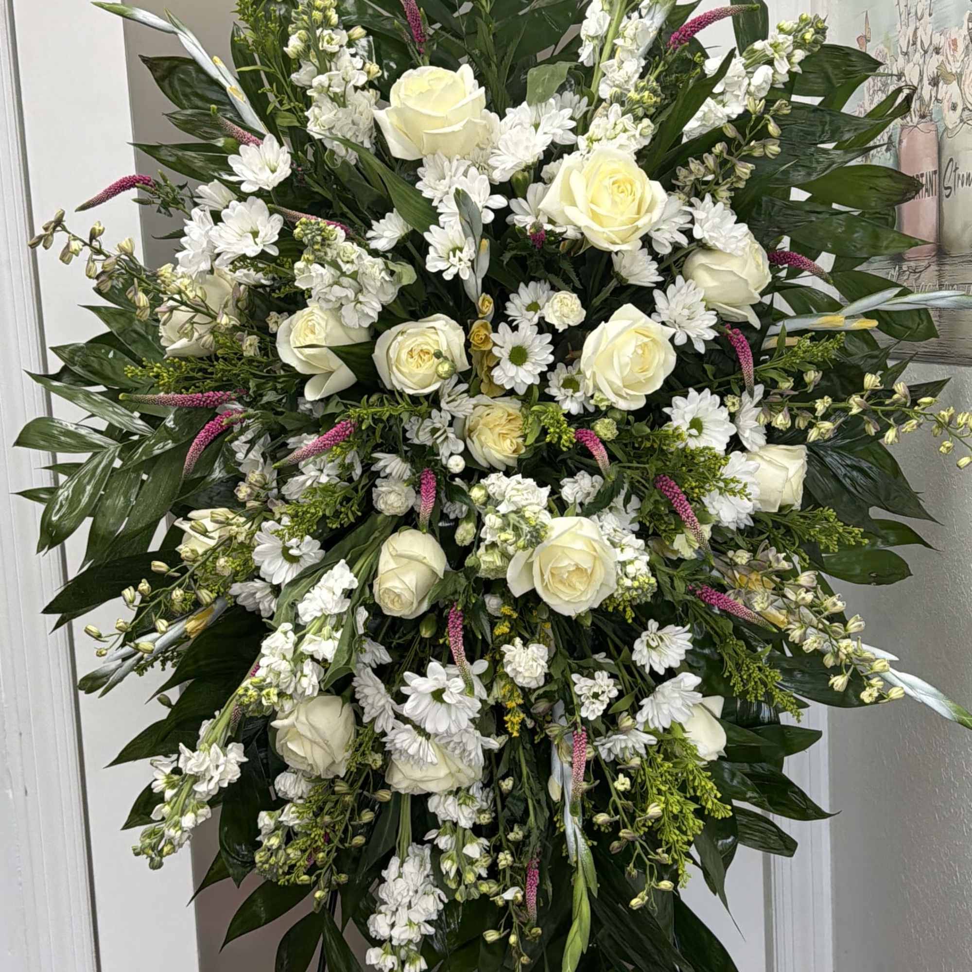 Large white floral standing spray with roses and daisies on an easel