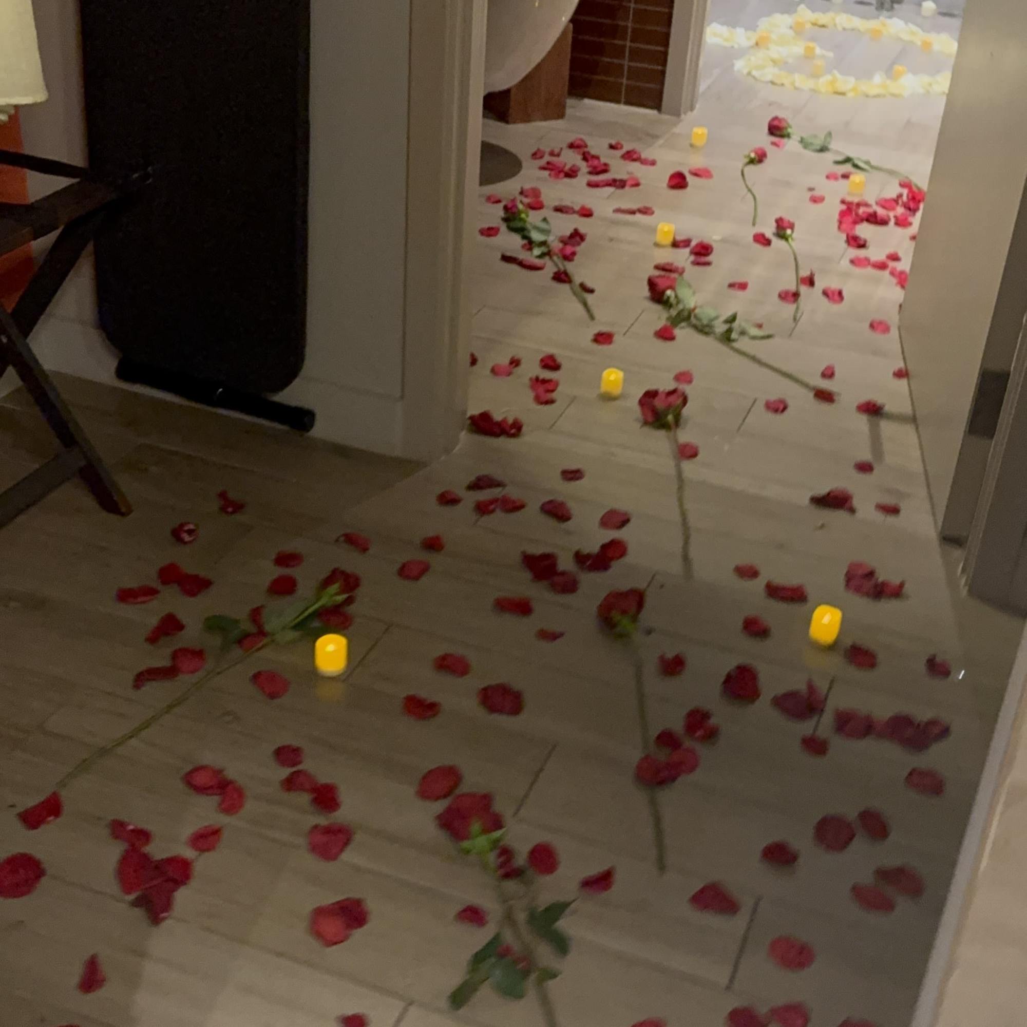 Rose petals and candles scattered along a hallway leading to a bathroom