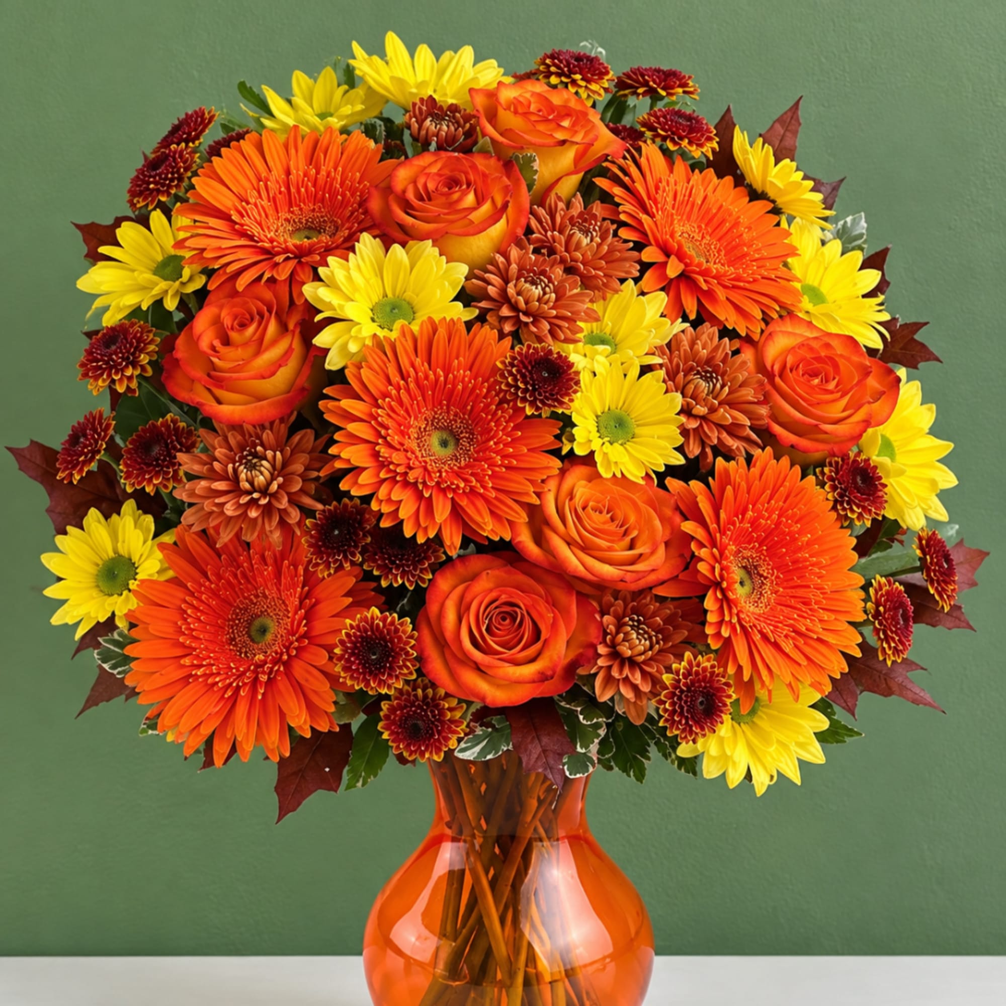 Orange and yellow mixed bouquet in an orange glass vase