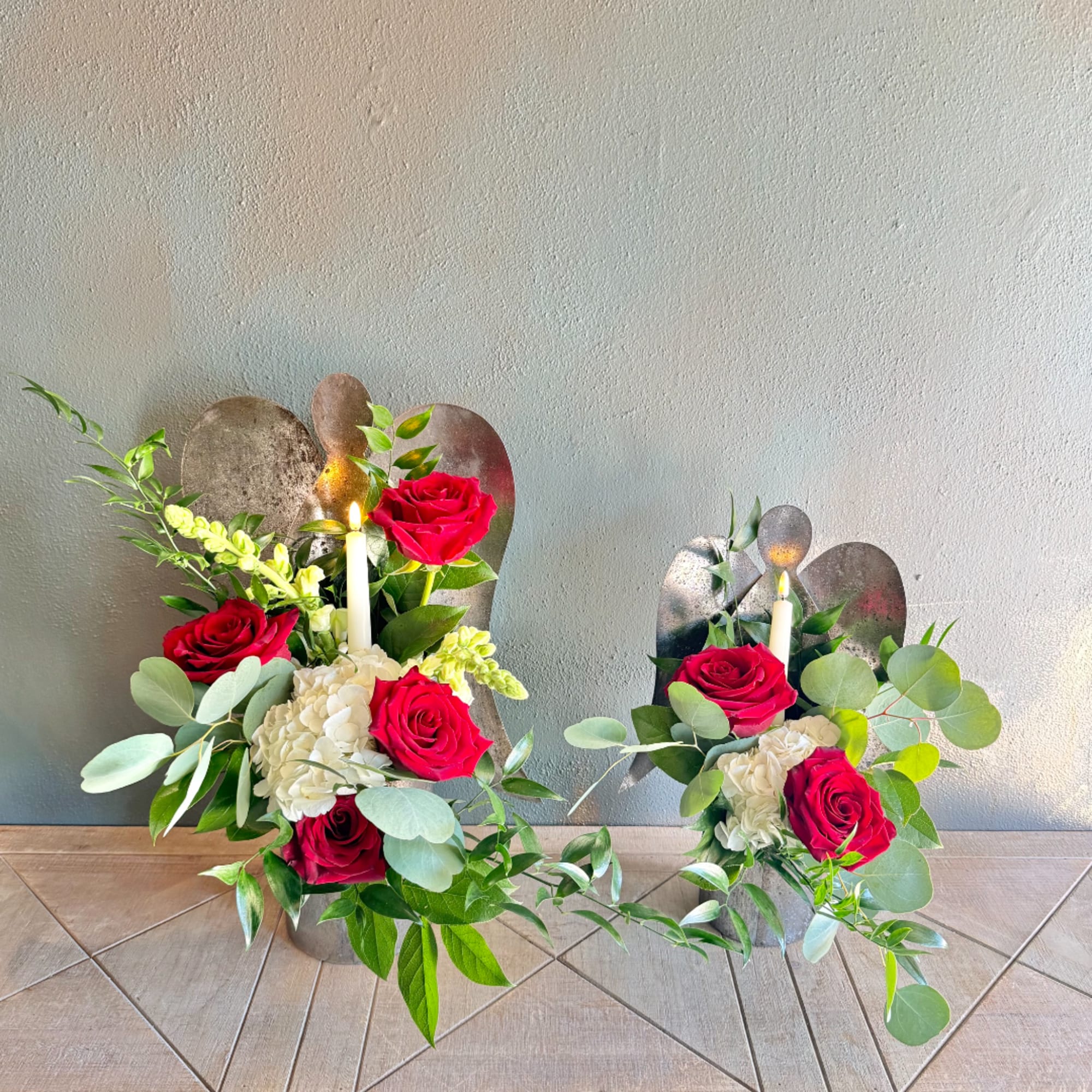 Two floral candle arrangements with red roses and white blooms in metal holders