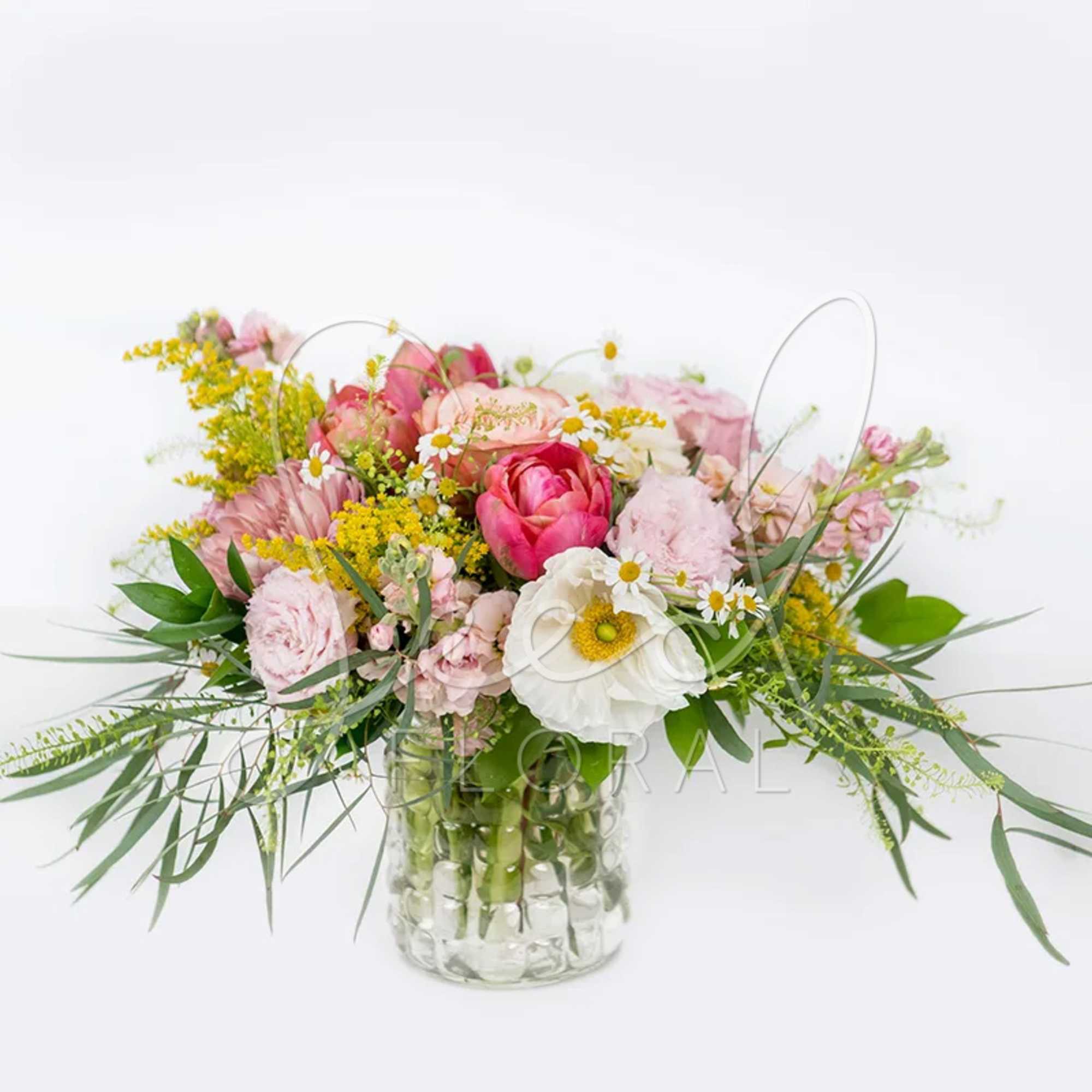 Low glass vase of pink and white mixed flowers with yellow accents and airy greenery.