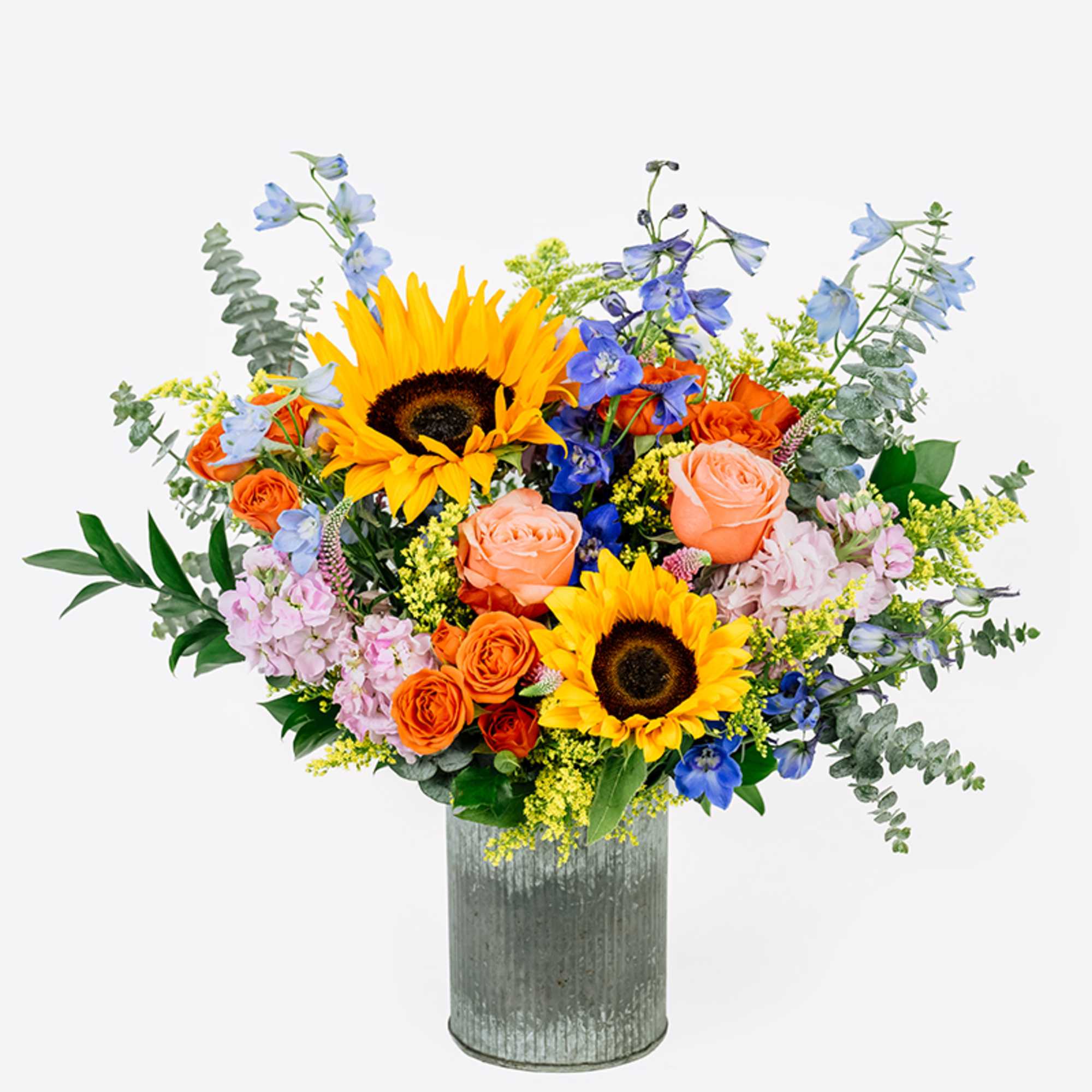 Mixed bouquet with sunflowers, roses, and blue flowers in a metal vase