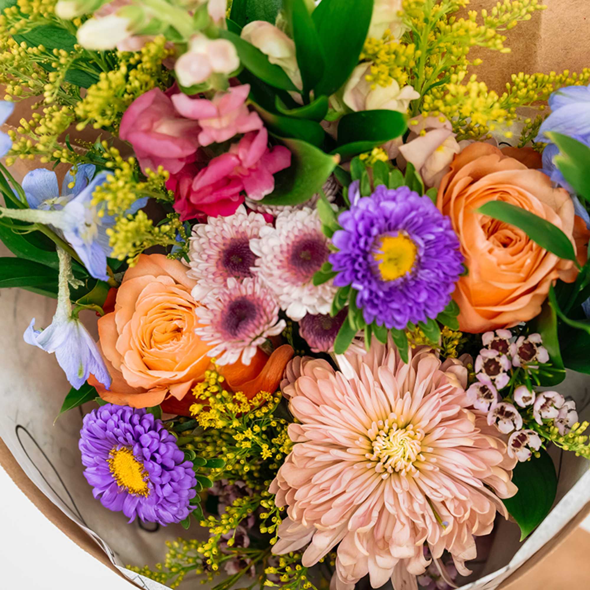 Mixed bouquet with peach roses, purple daisies, and pink blooms
