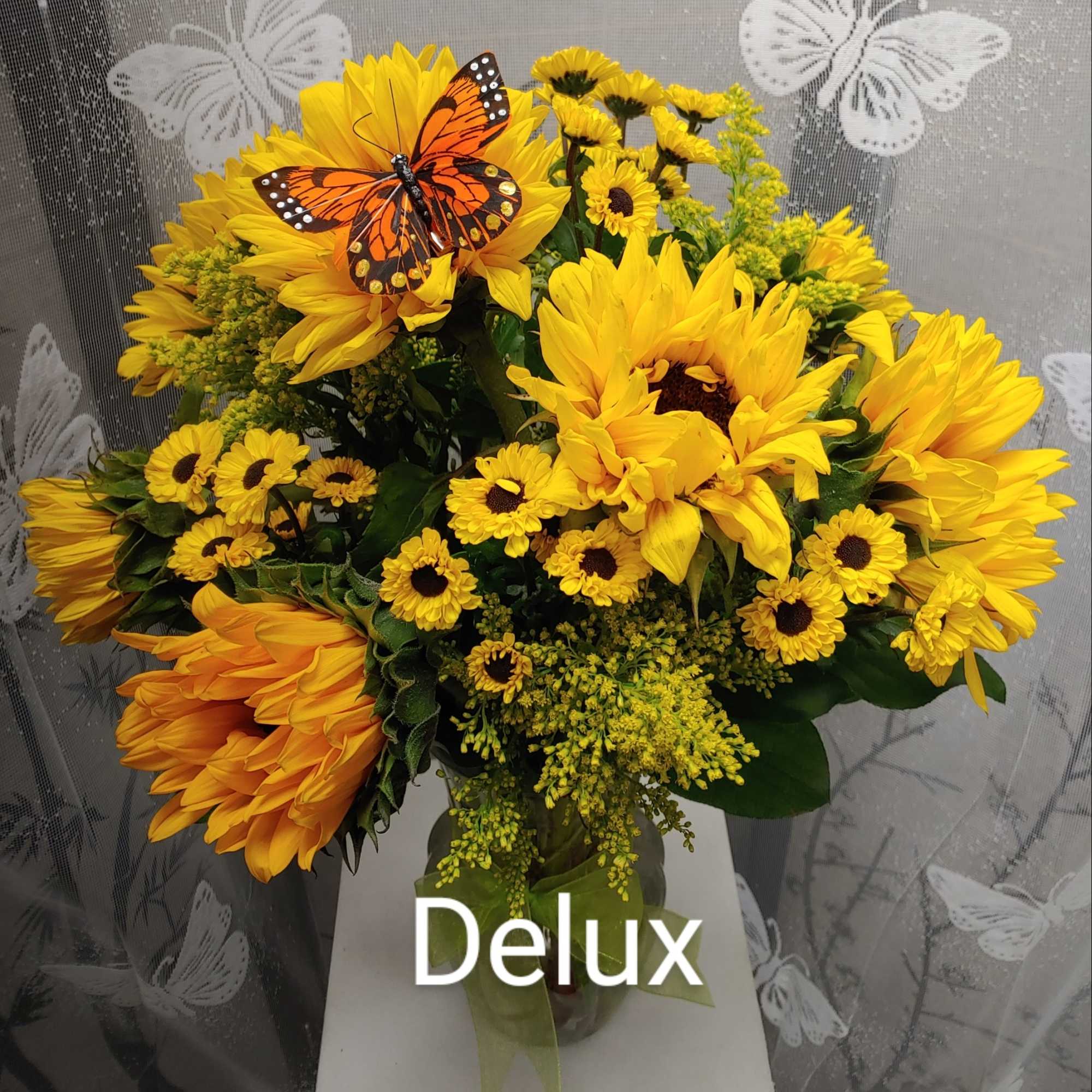 Yellow sunflower bouquet with small daisy-like blooms in a glass vase