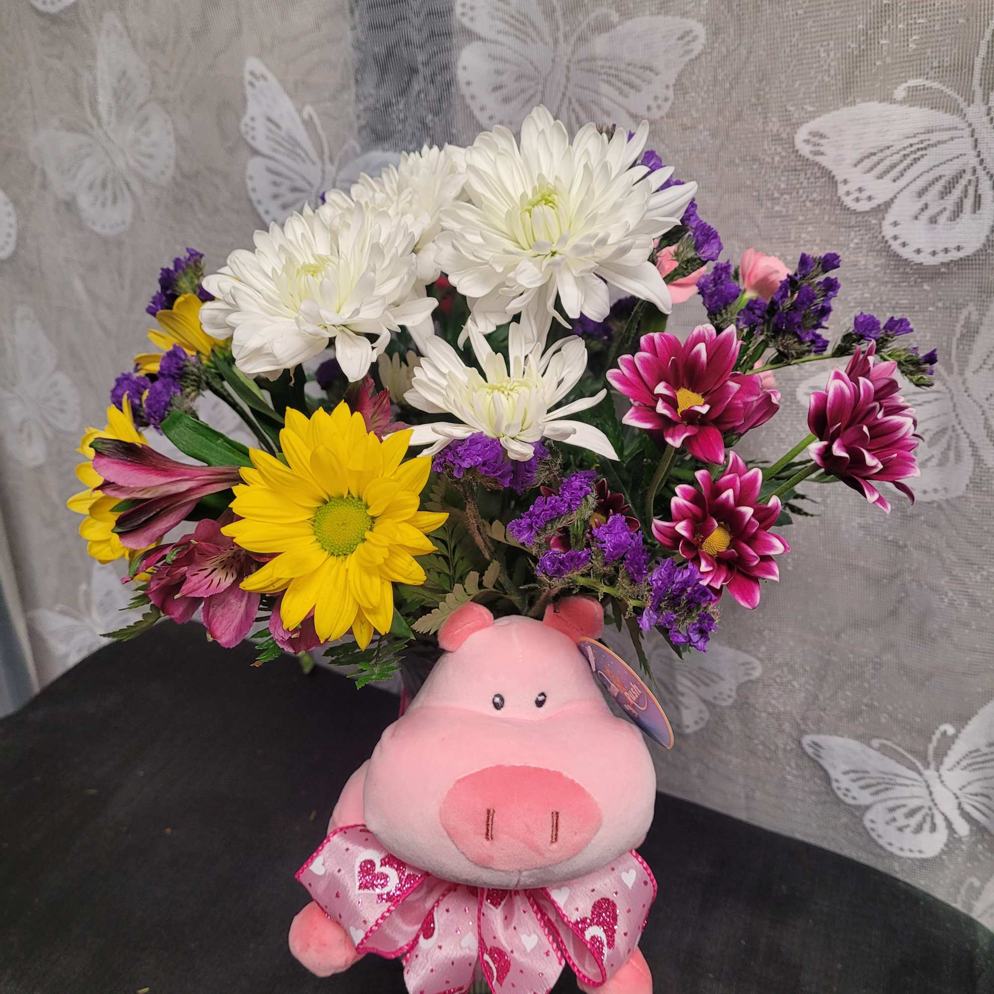 Bouquet of mixed daisies with a pink plush pig and ribbon