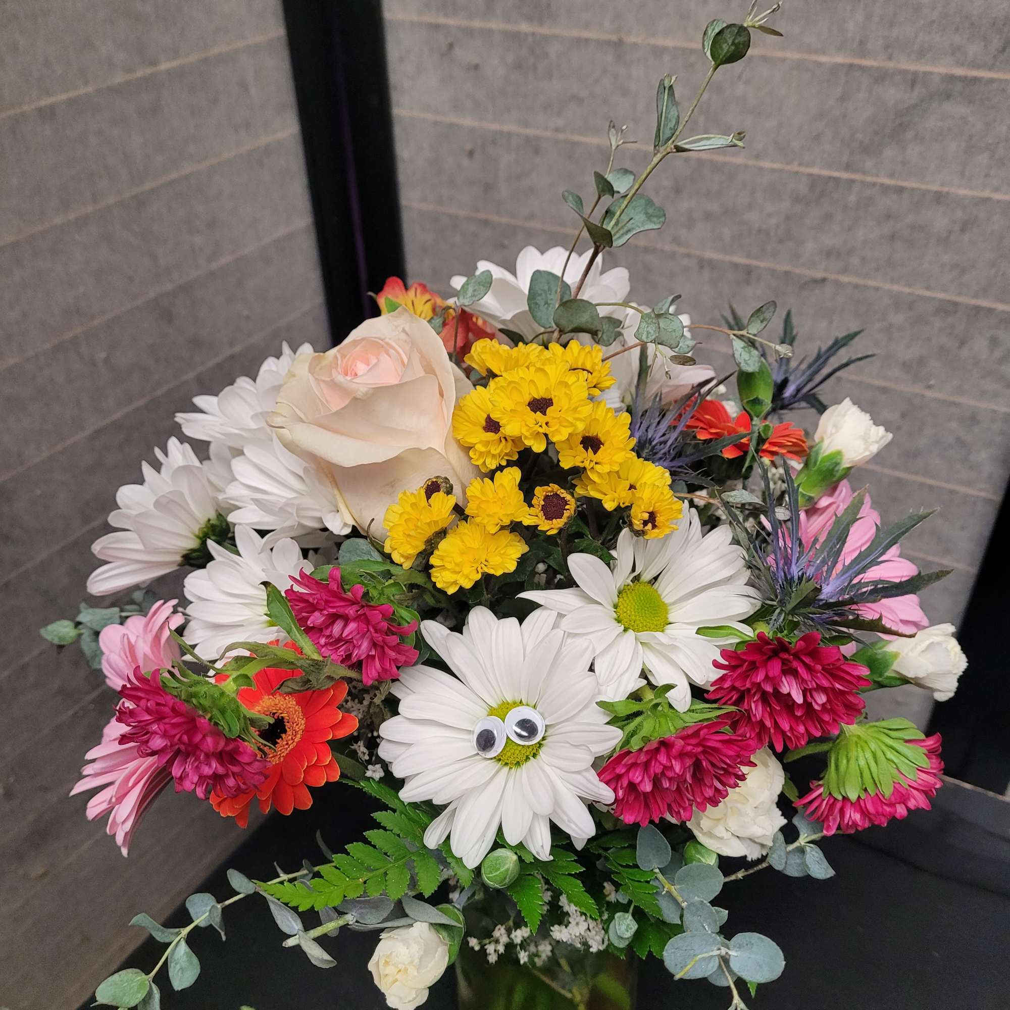Mixed bouquet of daisies, roses, and chrysanthemums in a glass vase