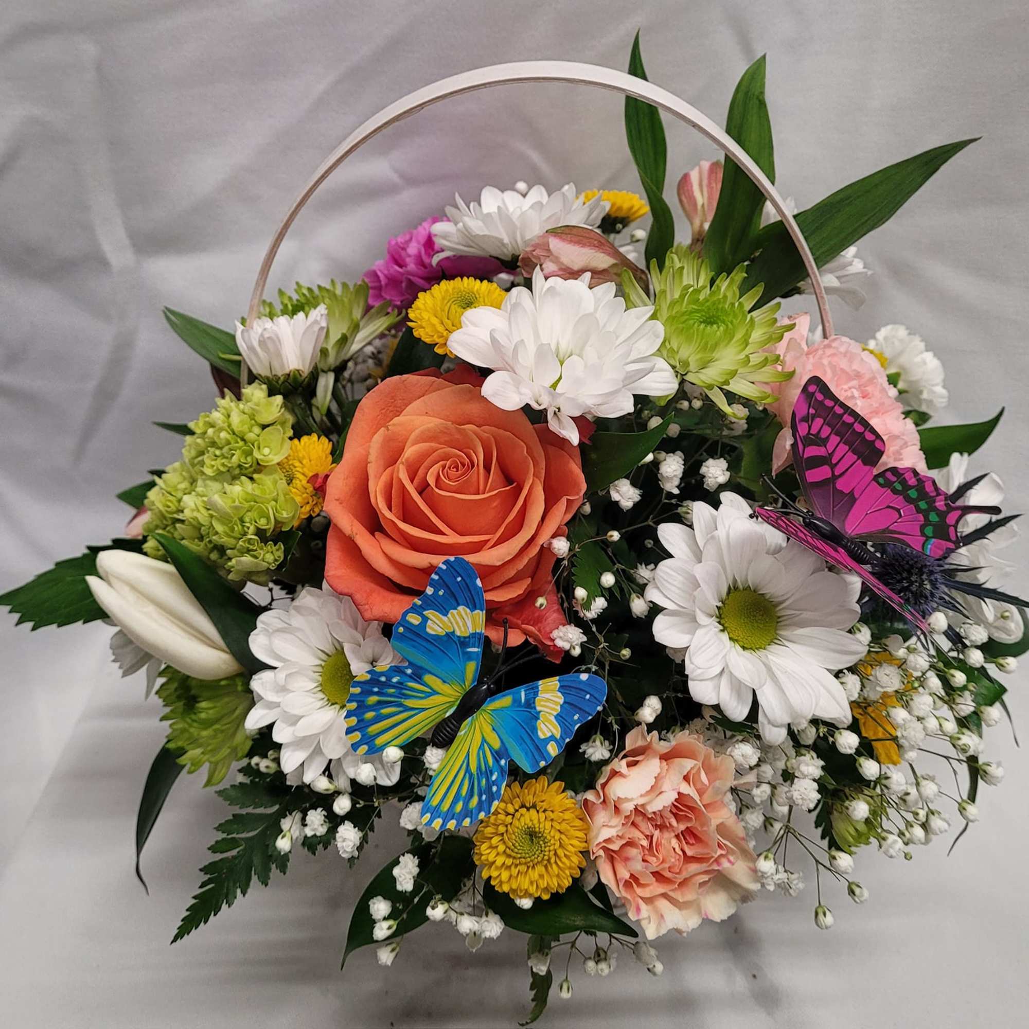Basket arrangement of mixed flowers with two decorative butterflies