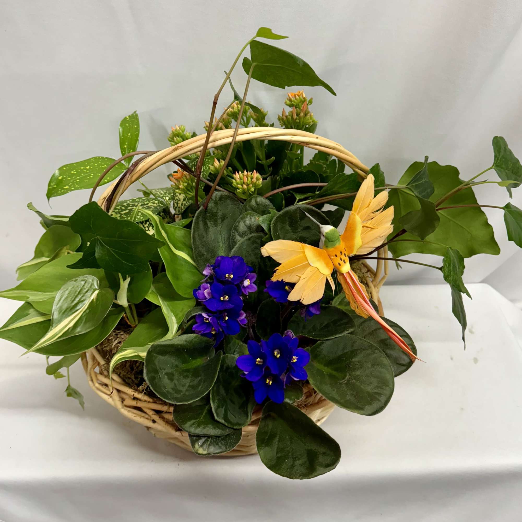 Basket planter with purple flowers and a yellow bird decoration