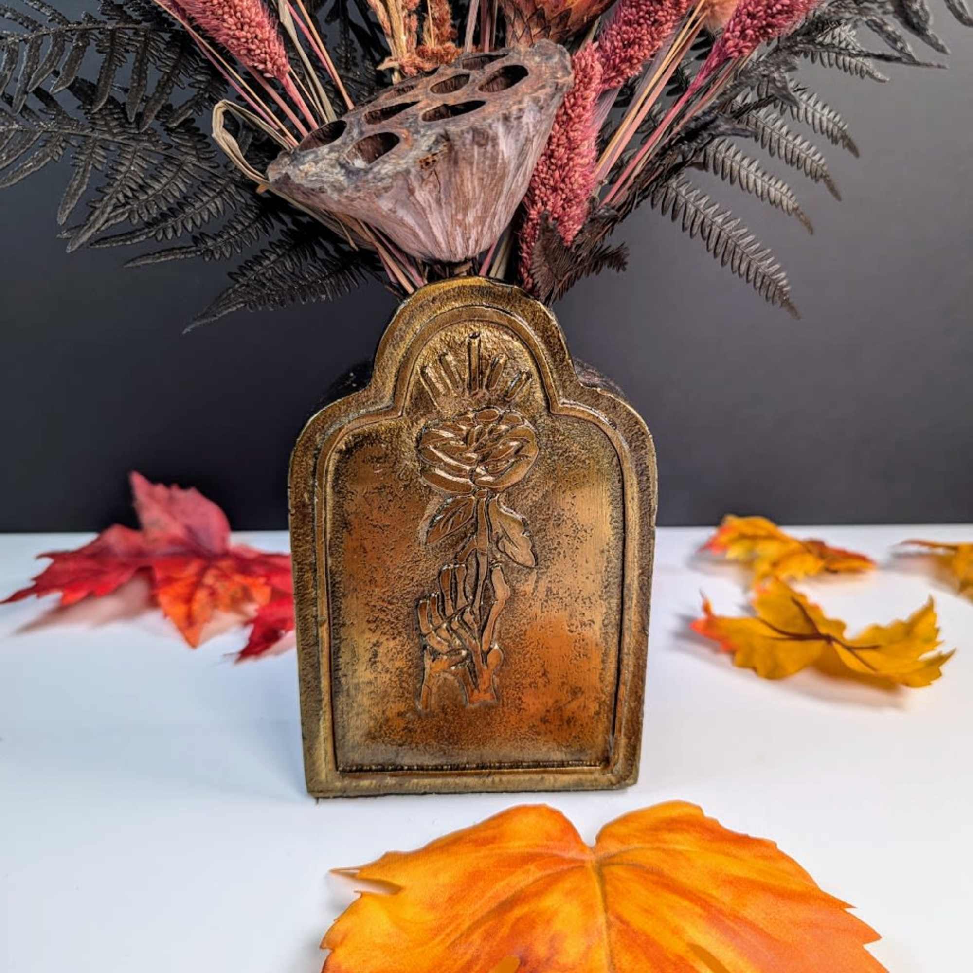 Autumn arrangement in a bronze vase with pink dried grasses and seed pods