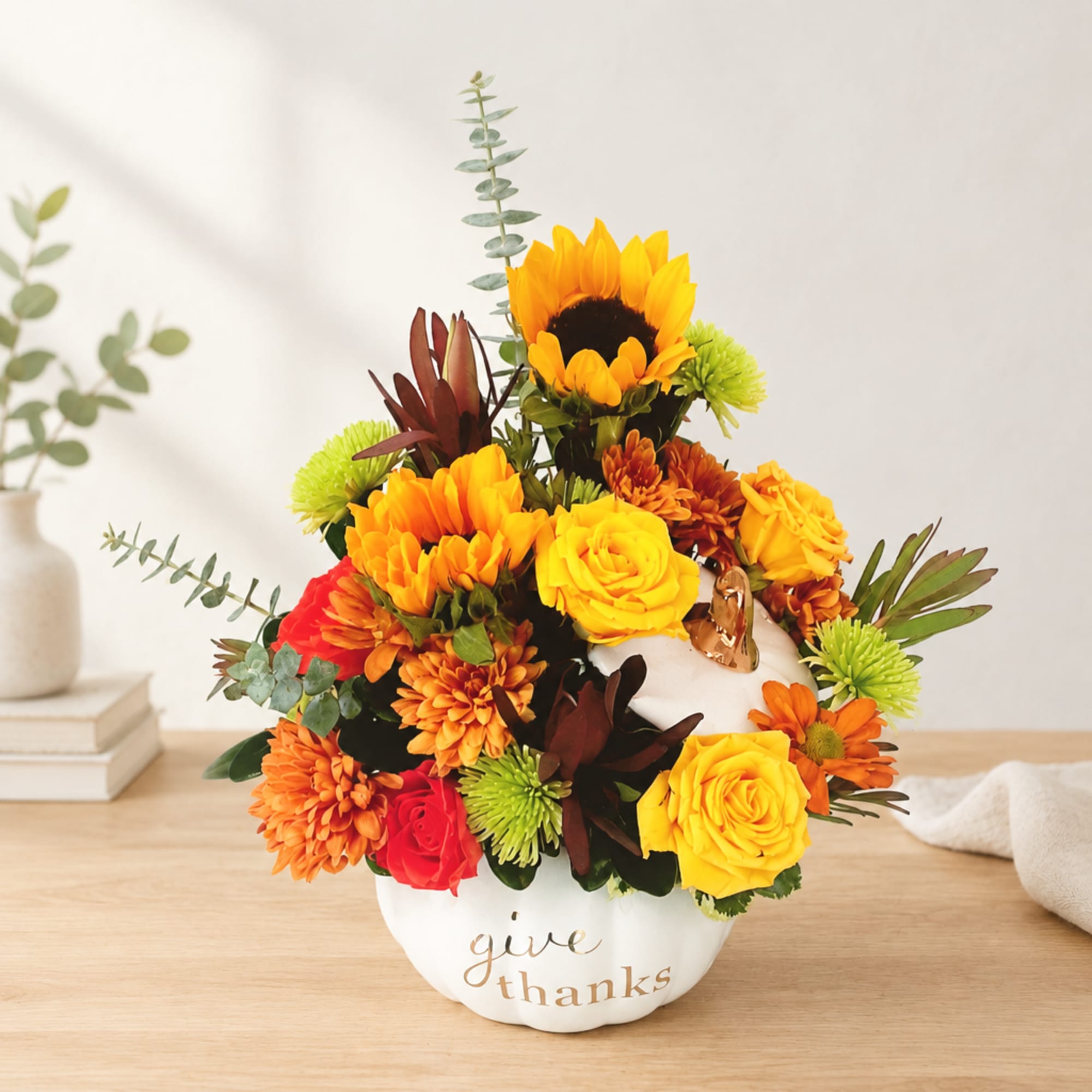 Bright mixed flower arrangement in a white pumpkin-shaped vase