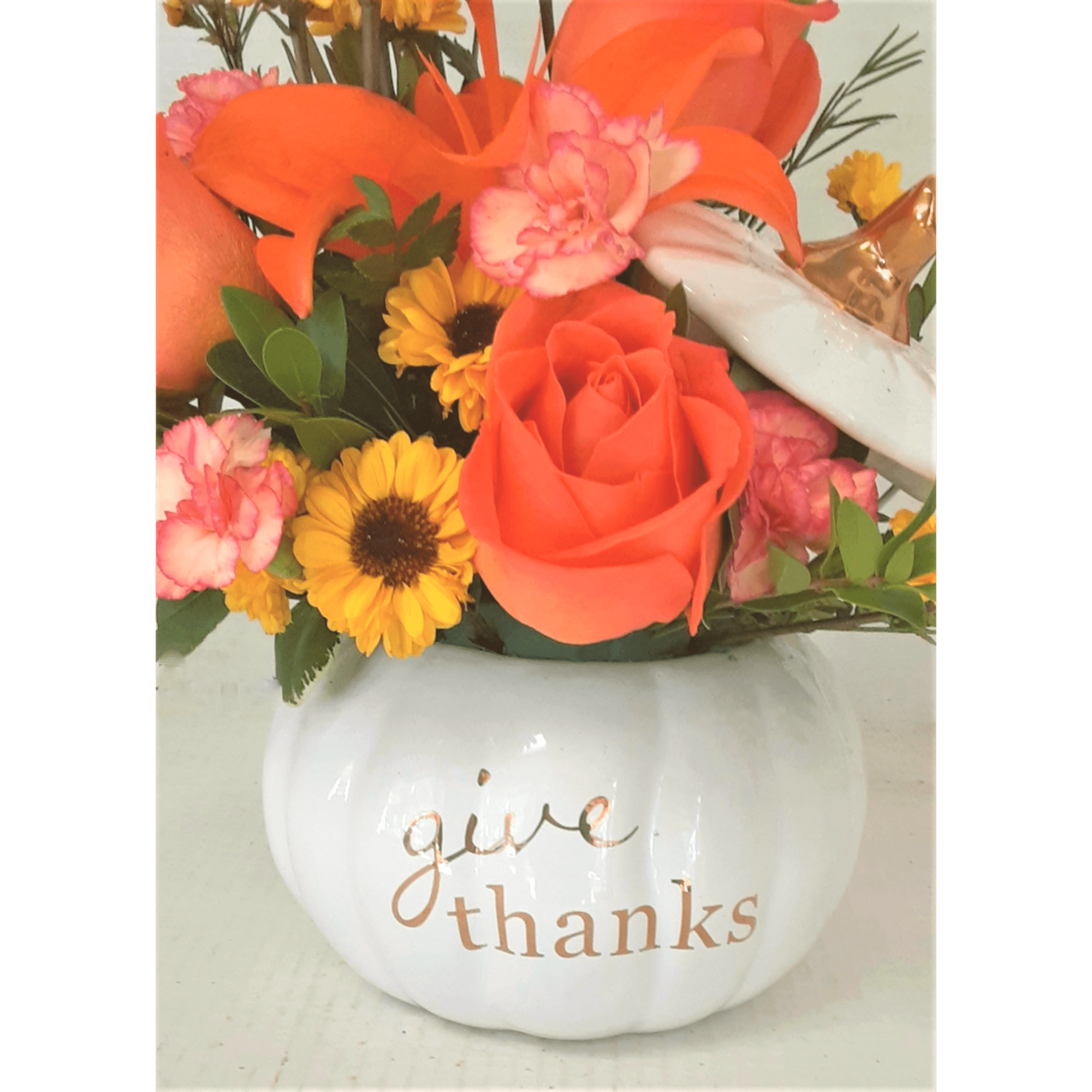 Orange and pink flower arrangement in a white pumpkin vase