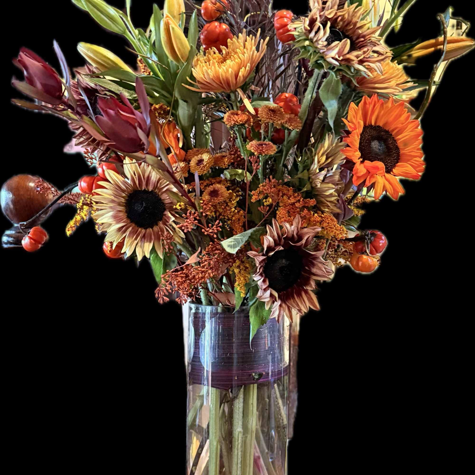 Autumn bouquet with sunflowers and orange blooms in a clear glass vase