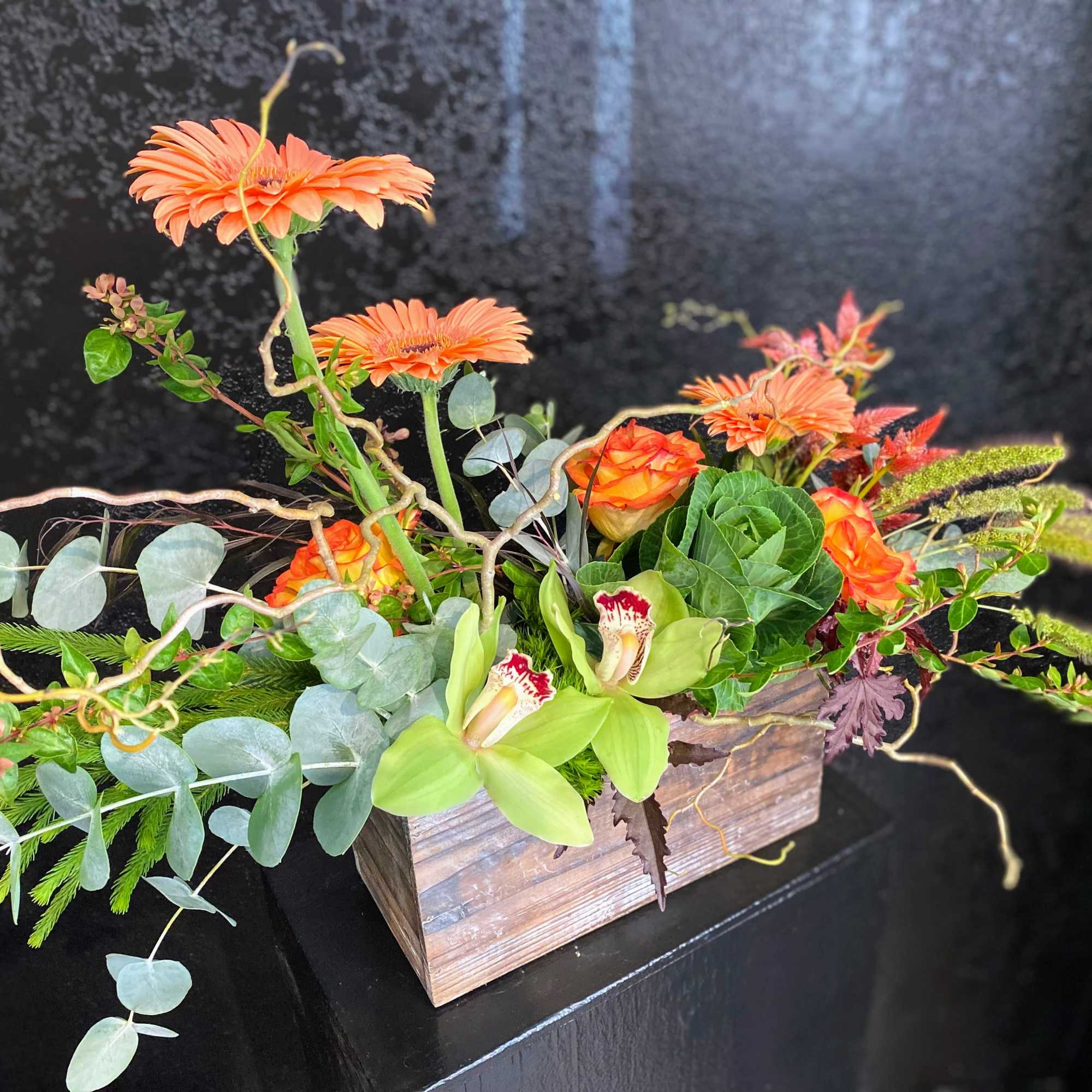 Orange flowers in a rustic wooden box with trailing greenery