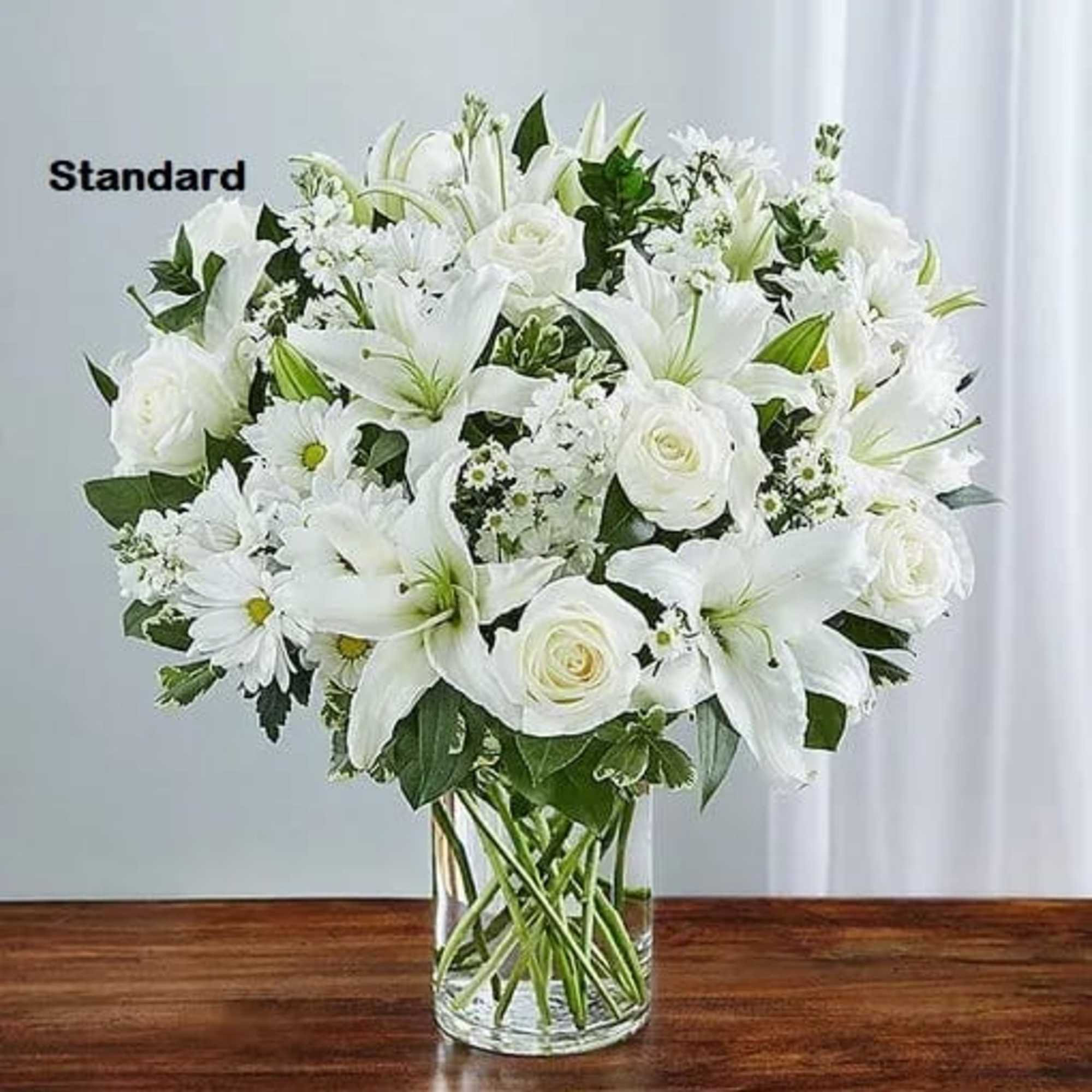 White lilies and roses arranged in a clear glass vase
