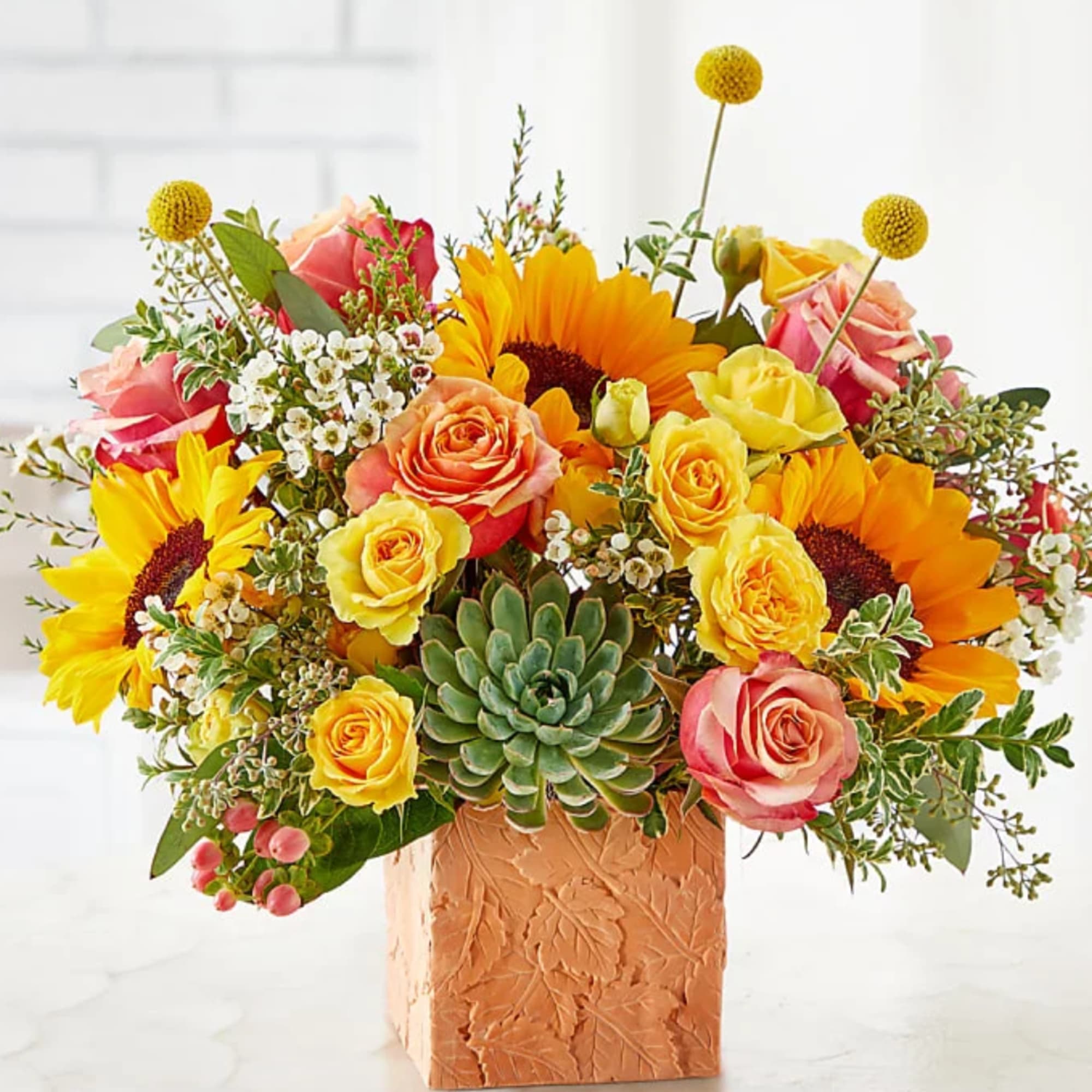 Colorful bouquet of roses and sunflowers in a textured square vase