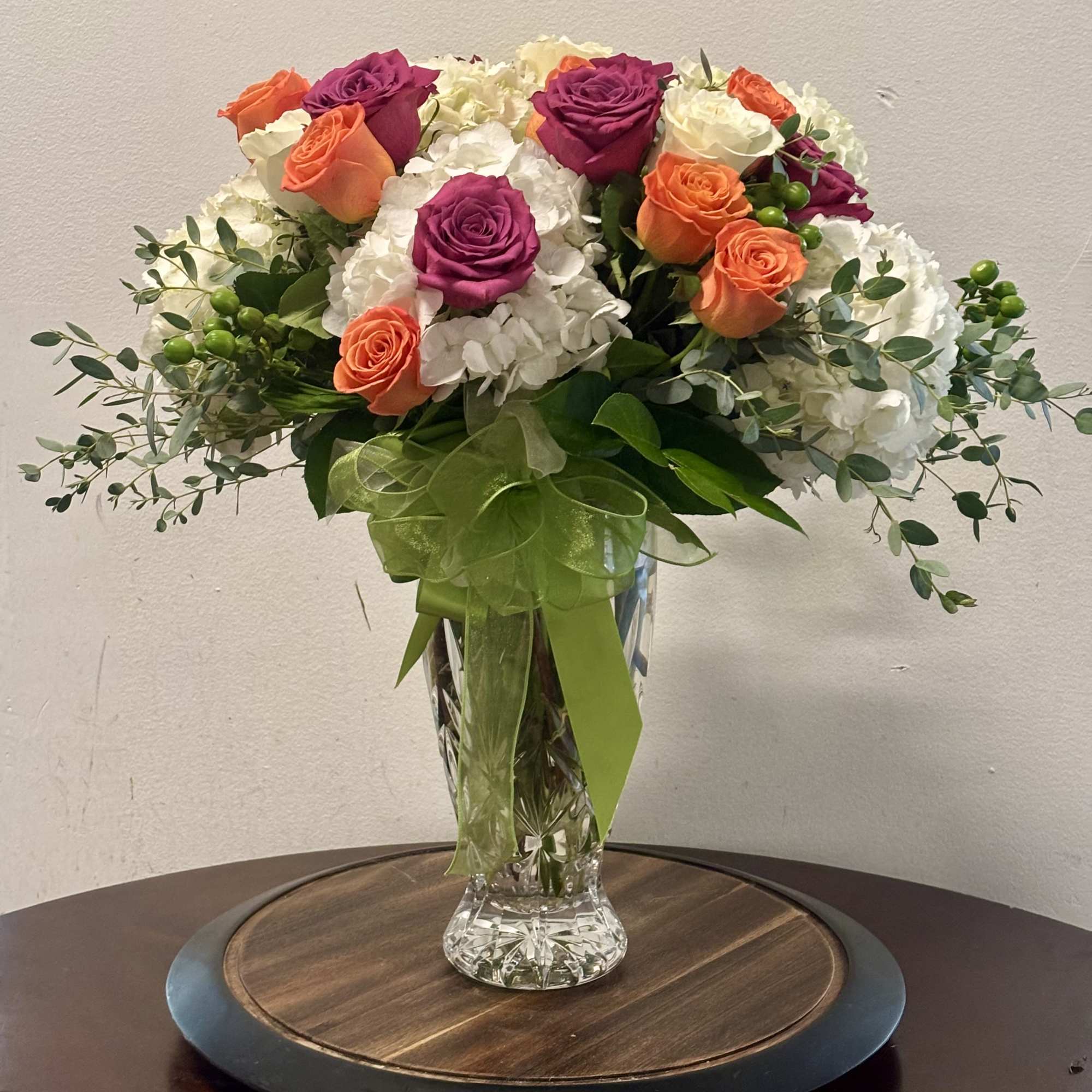 Bouquet of orange and magenta roses in a clear glass vase