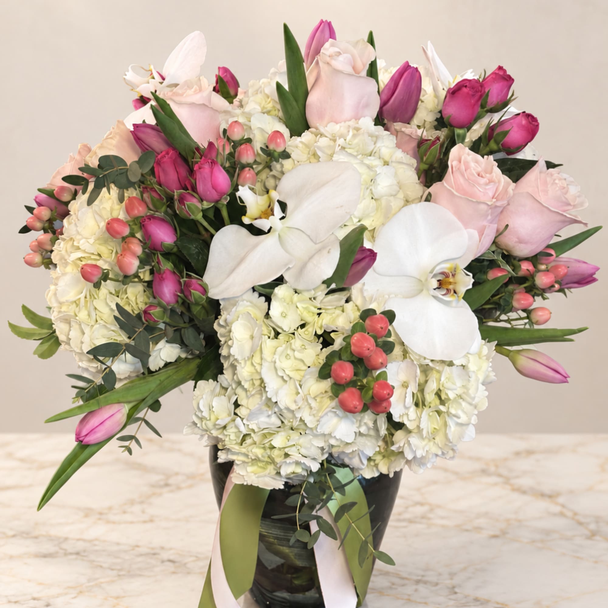 Pink roses, white orchids, and hydrangeas in a black vase