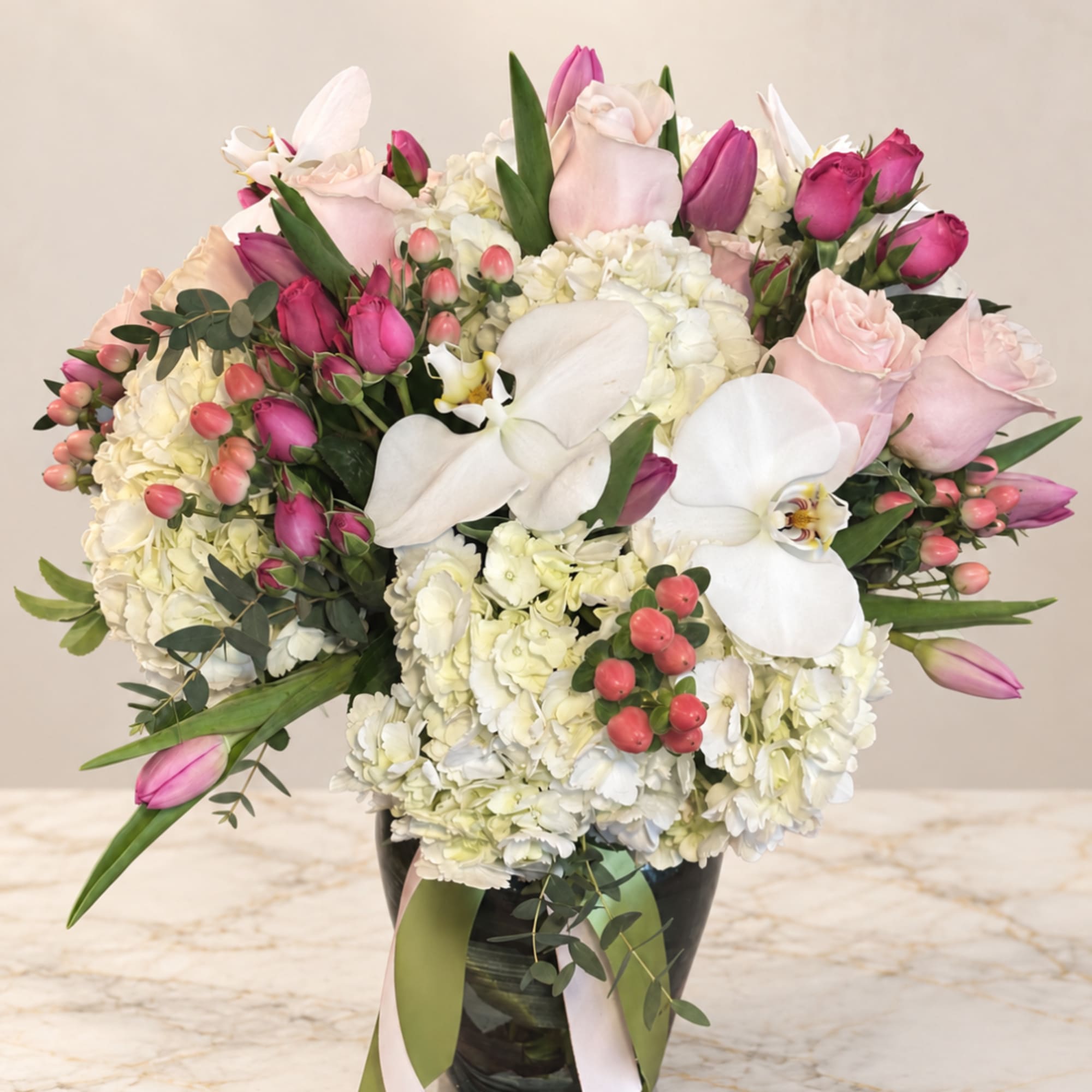 Pink and white floral arrangement in a black vase