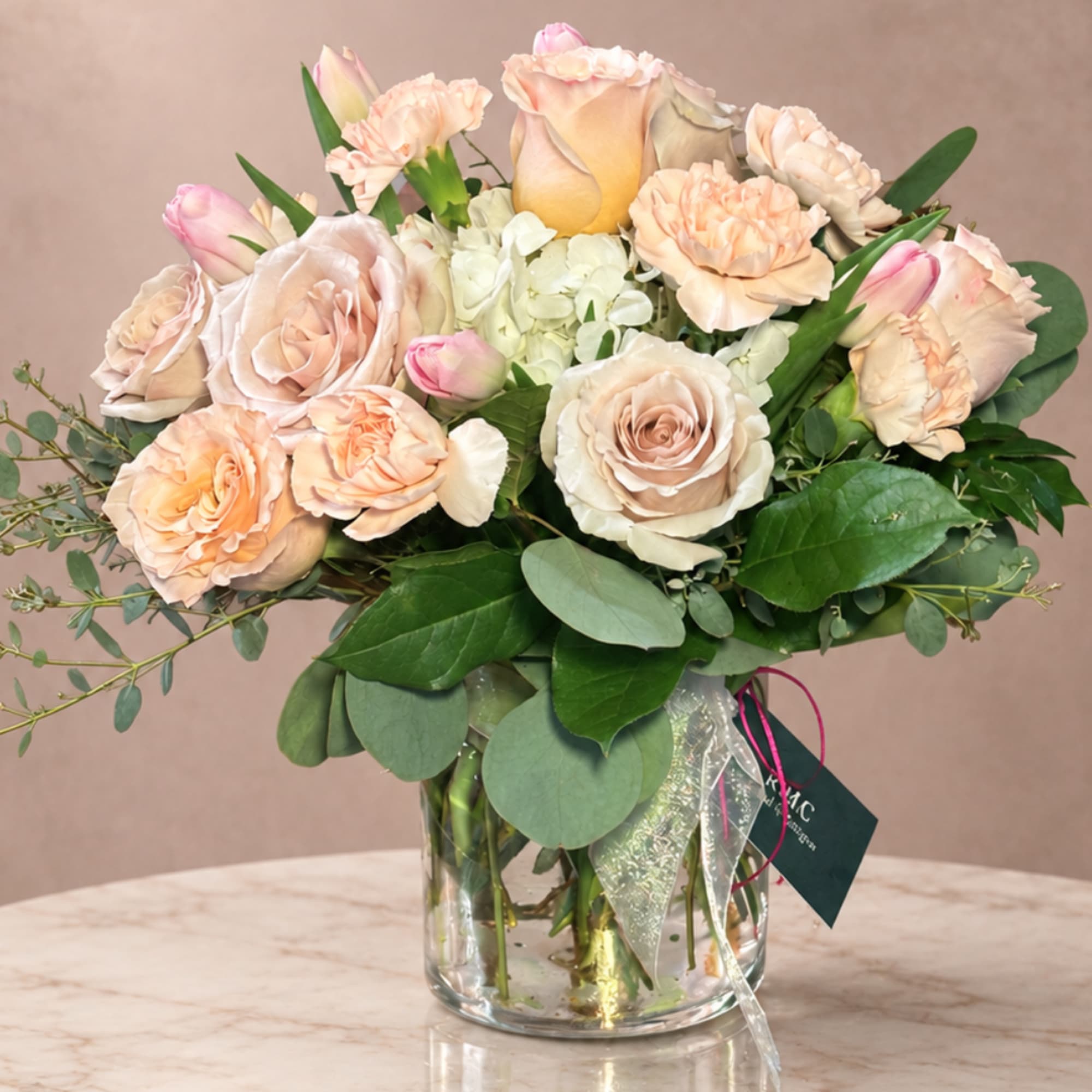 Blush roses and carnations arranged in a clear glass vase