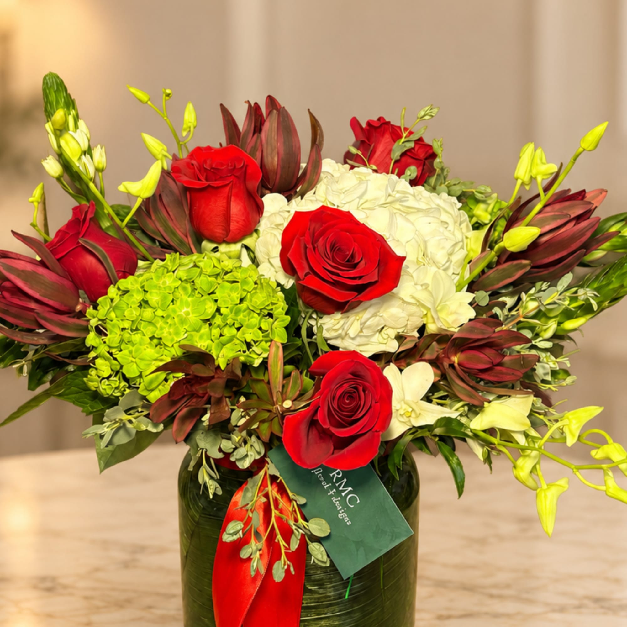 Red roses and white hydrangeas in a glass vase with green accents