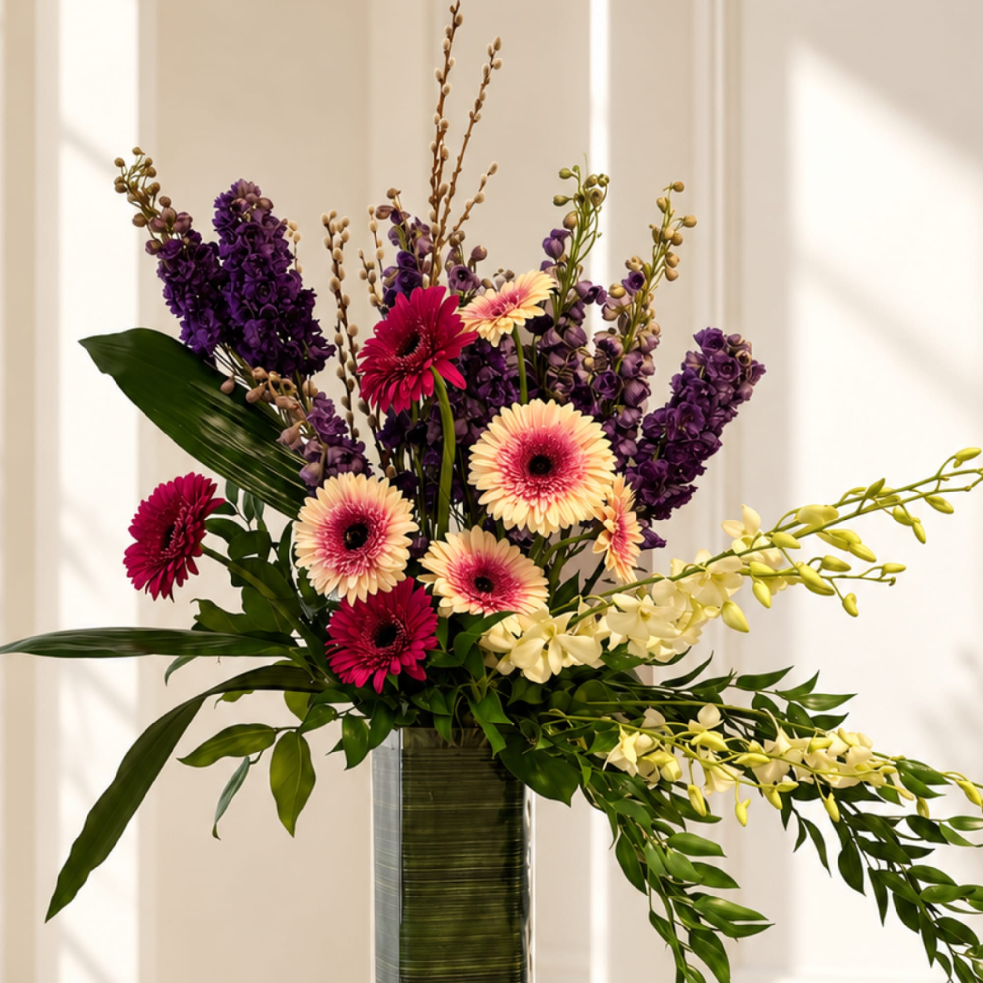 Tall mixed bouquet with purple and pink flowers in a glass vase