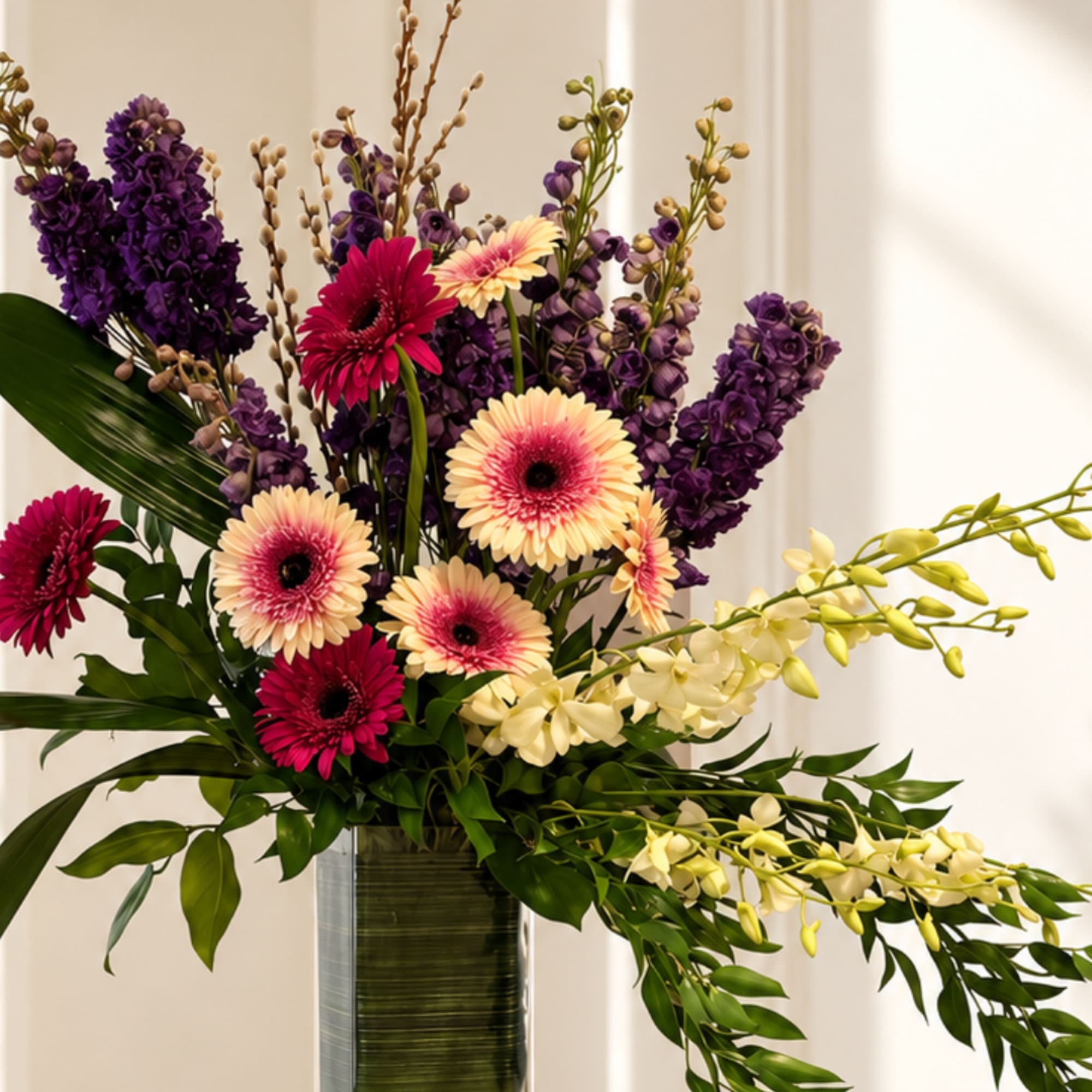 Tall mixed bouquet with purple and pink flowers in a glass vase