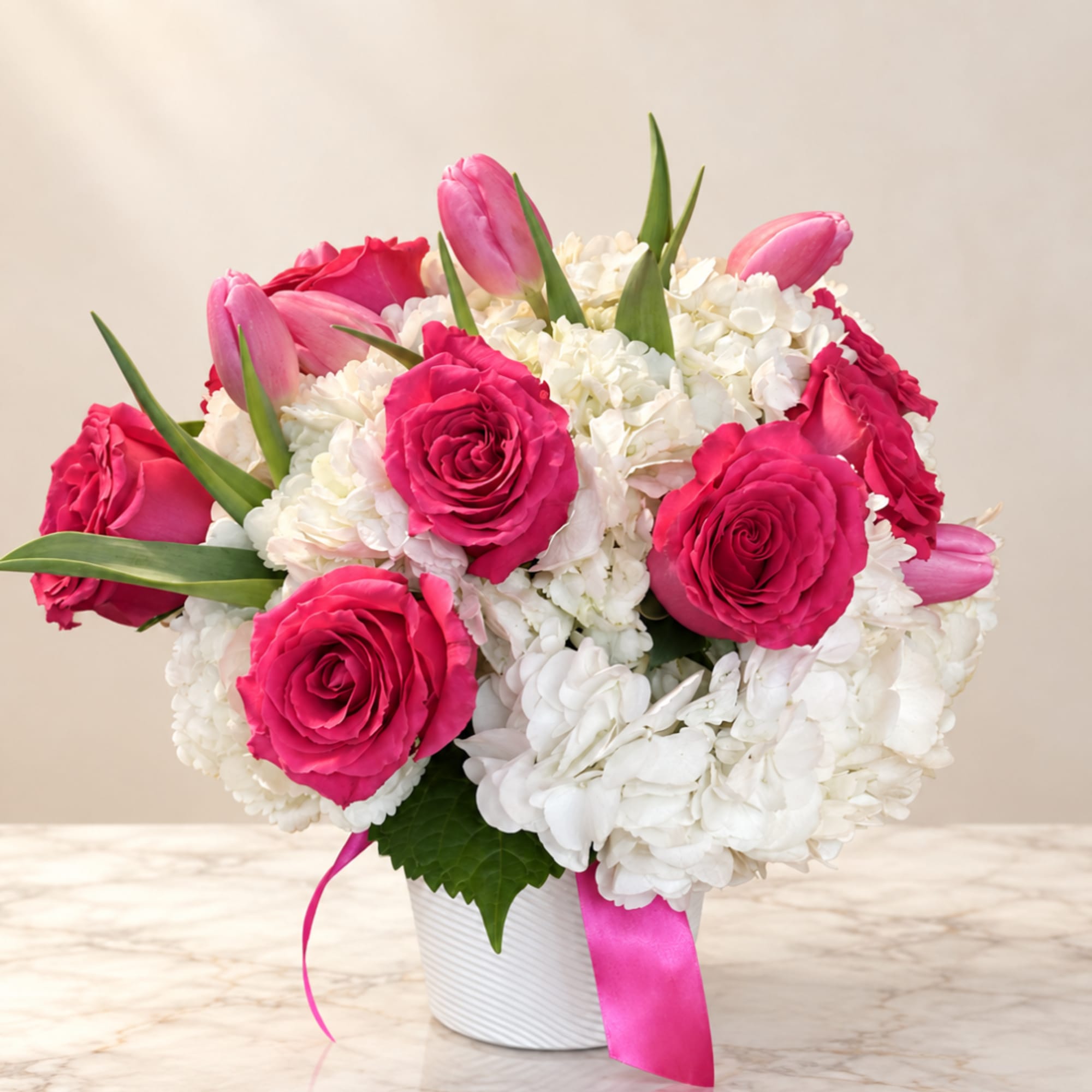 Pink roses and tulips in a white vase with white hydrangeas
