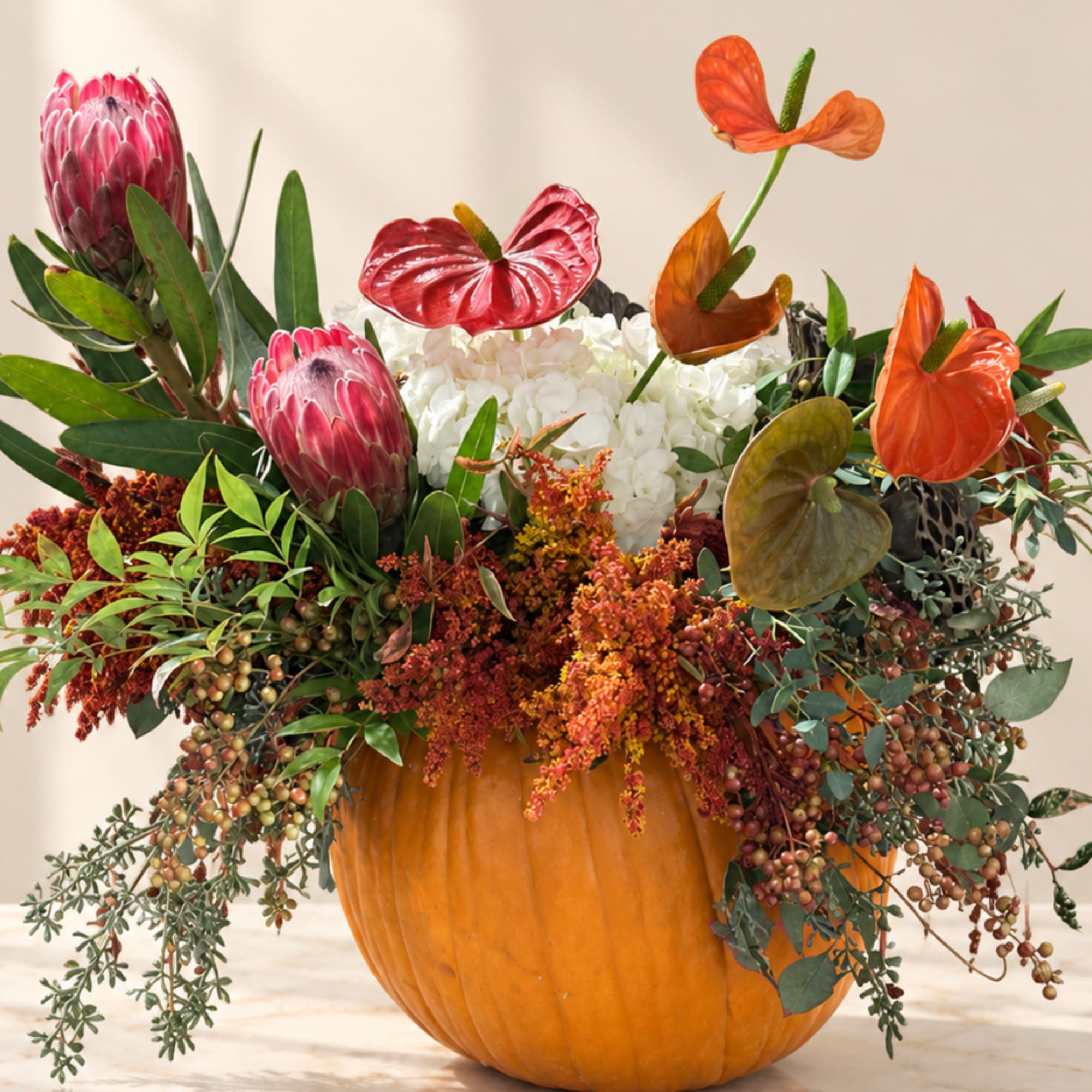 Tropical floral arrangement in a pumpkin container with orange and pink blooms