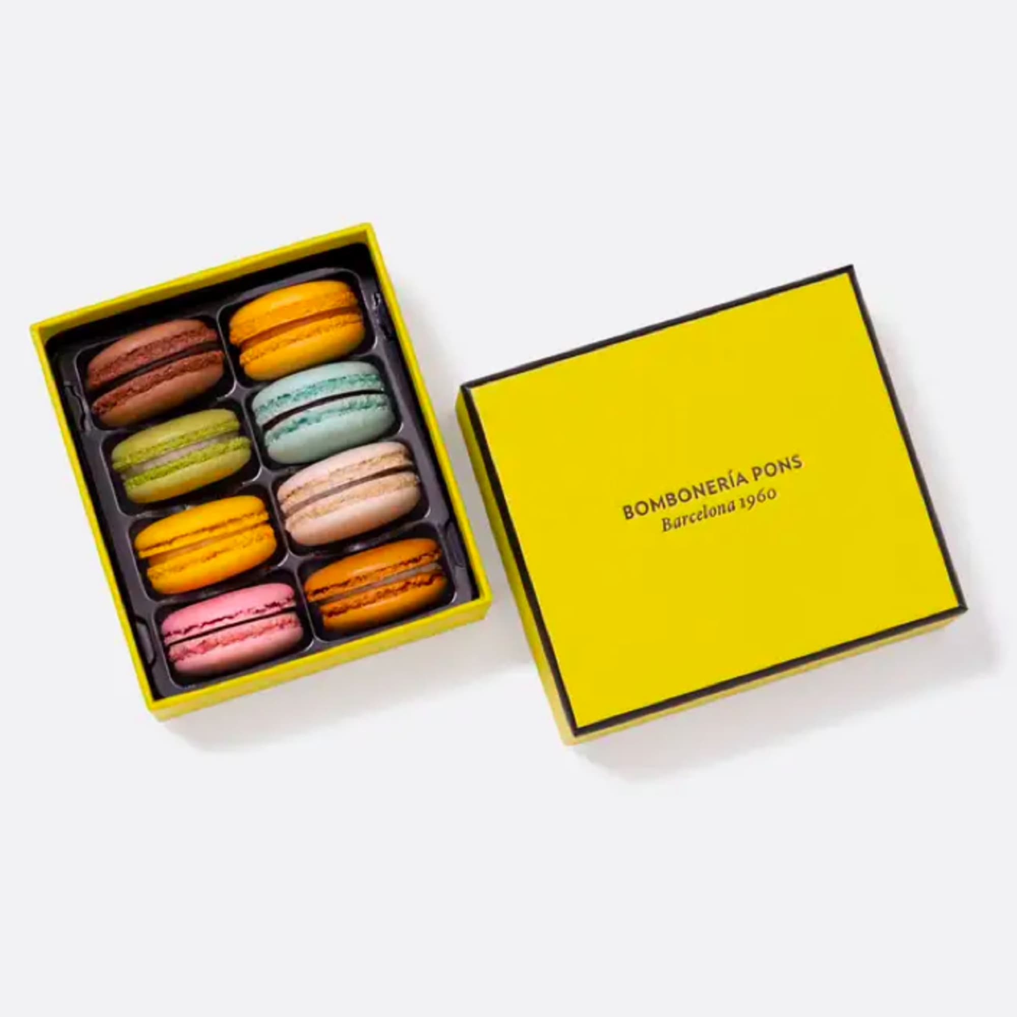 Box of colorful macarons with a yellow lid beside it